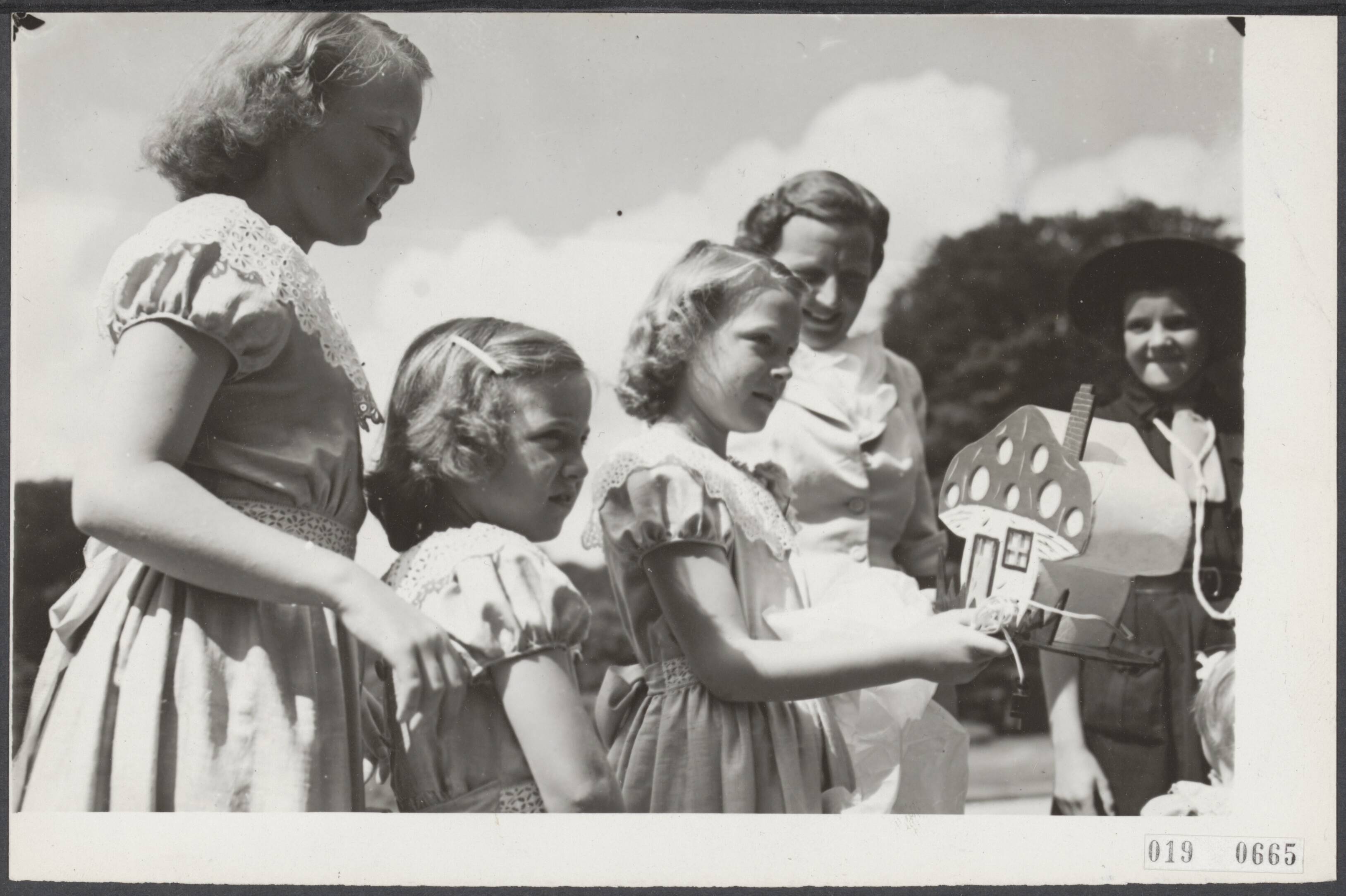 Fotocollectie Elsevier Binnenland — Viering van de verjaardag van prinses Irene, die 11 jaar oud wordt, in de tuin van paleis Soestdijk. Padvindsters uit Heemsted, die in Soest kamperen, e bieden als cadeau een schemerlampje in de vorm van een kabouterhuisje aan — Foto: ANP / RVD of rechtenvrij. Licentie: Set B: Rechtenvrij / Publiek Domein. Bron: Nationaal Archief. http://hdl.handle.net/10648/adc749ca-d0b4-102d-bcf8-003048976d84