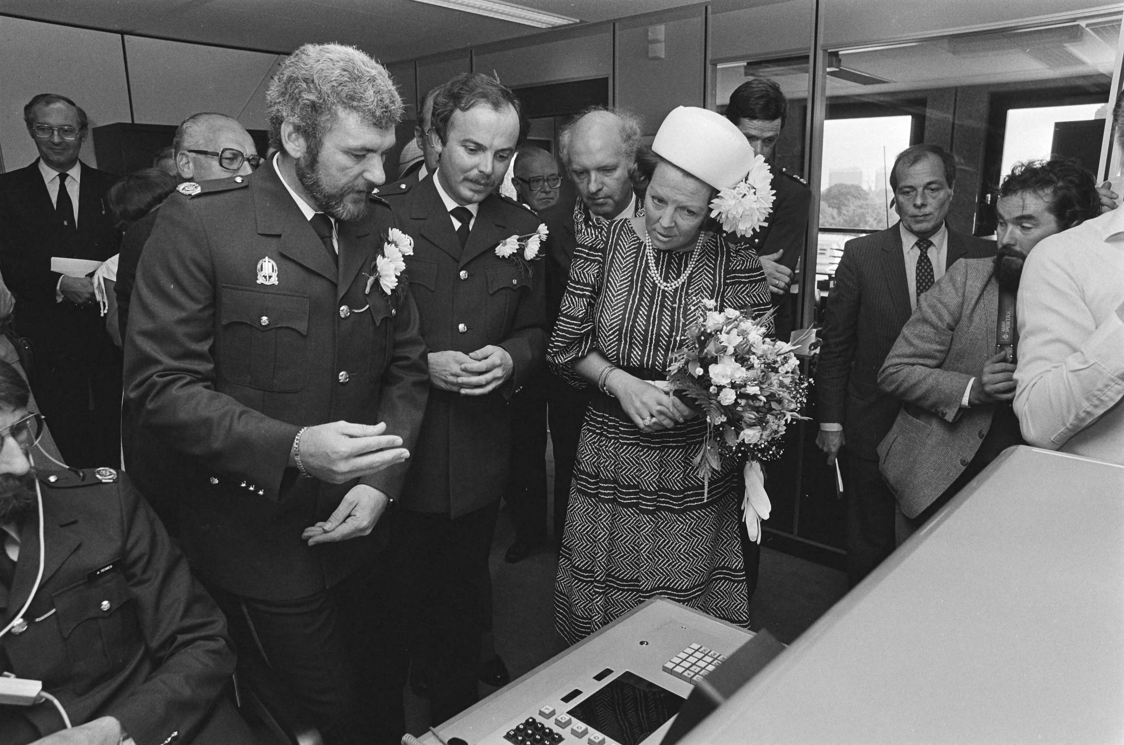 Opening van nieuwe hoofdburo van politie in Den Haag door Koningin Beatrix — Brigadier Debets (l), hoofdinspecteur van politie dhr. F.H.C.Born, Beatrix (r) tijdens rondleiding in meldkamer — Foto: Antonisse, Marcel / Anefo. Licentie: Set B: Rechtenvrij / Publiek Domein. Bron: Nationaal Archief. http://hdl.handle.net/10648/ace73394-d0b4-102d-bcf8-003048976d84