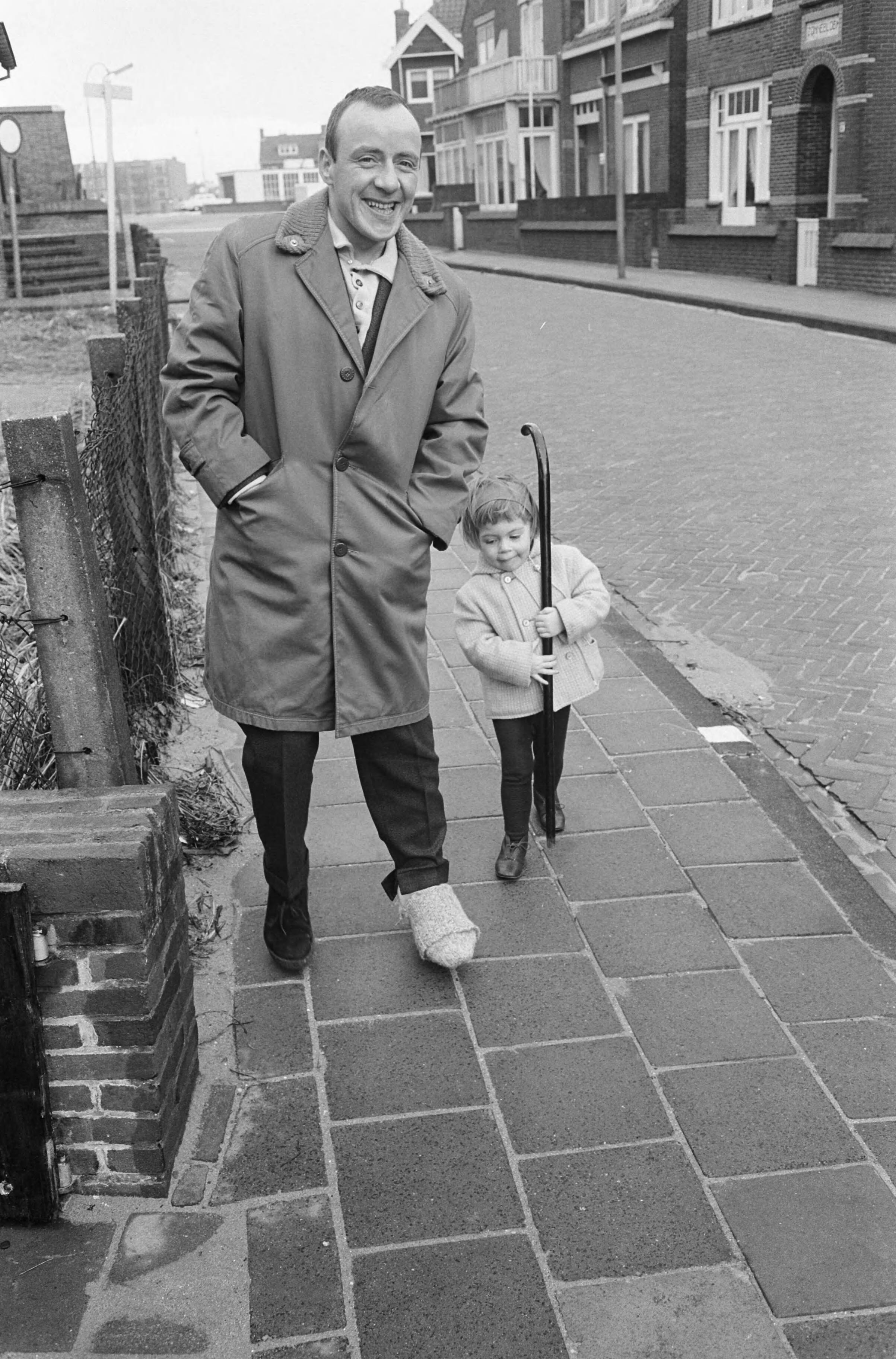 Fotocollectie Anefo — Johnnie Kraaijkamp aan beterende hand. Met loopgids maakt hij een wandeling met zijn dochter die zijn wandelstok draagt — Foto: Pot, Harry / Anefo. Licentie: Set B: Rechtenvrij / Publiek Domein. Bron: Nationaal Archief. http://hdl.handle.net/10648/a9f8c08a-d0b4-102d-bcf8-003048976d84