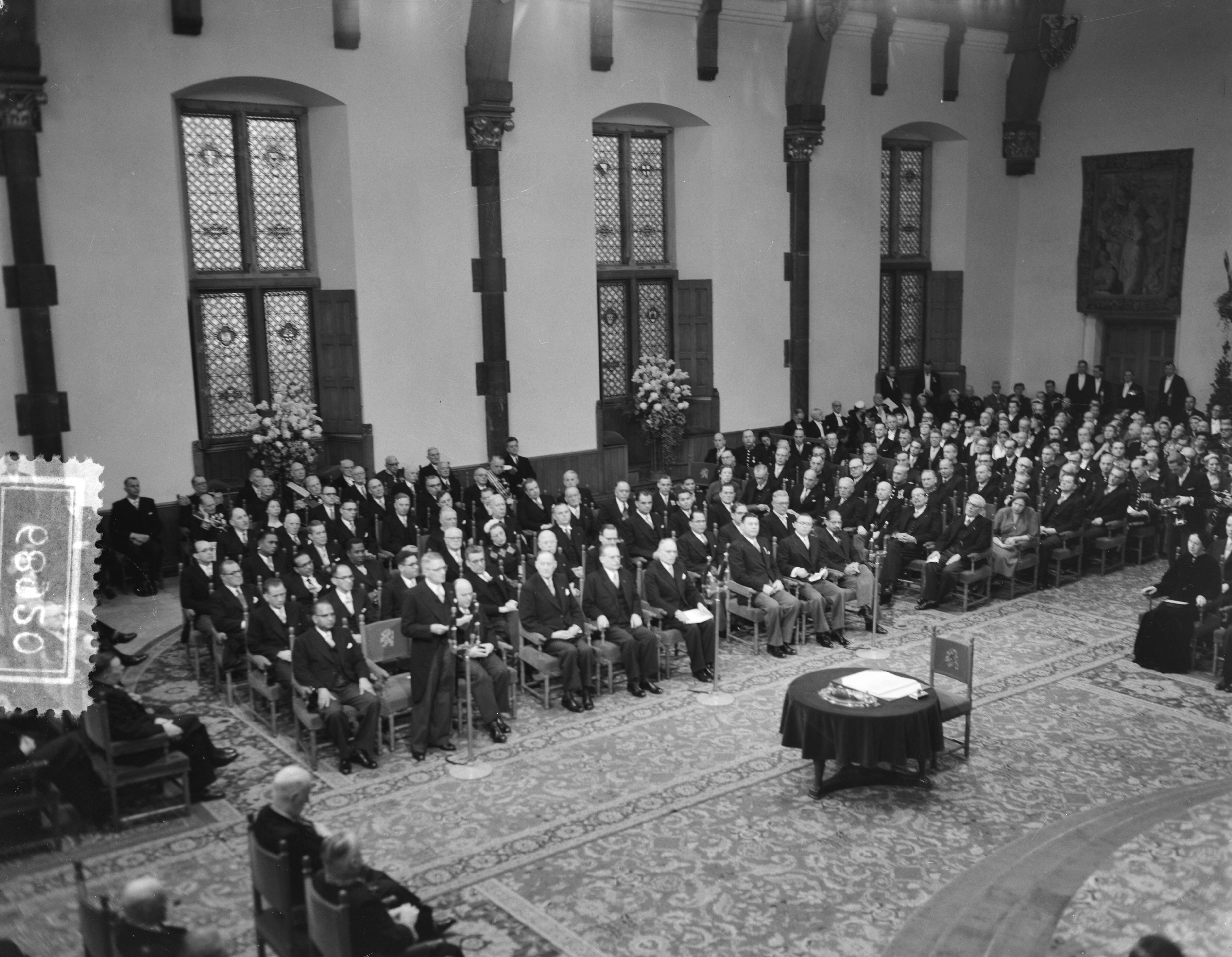Koningin Juliana ondertekent in een plechtige bijeenkomst in de Ridderzaal in Den Haag de Acte van Bevestiging van het Statuut voor het Koninkrijk — Ondertekening van de Acte van Bevestiging van het Statuut van het Koninkrijk in de Ridderzaal te Den Haag. Één van de ministers houdt een toespraak — Foto: Noske, J.D. / Anefo. Licentie: Set B: Rechtenvrij / Publiek Domein. Bron: Nationaal Archief. http://hdl.handle.net/10648/a92e1c86-d0b4-102d-bcf8-003048976d84
