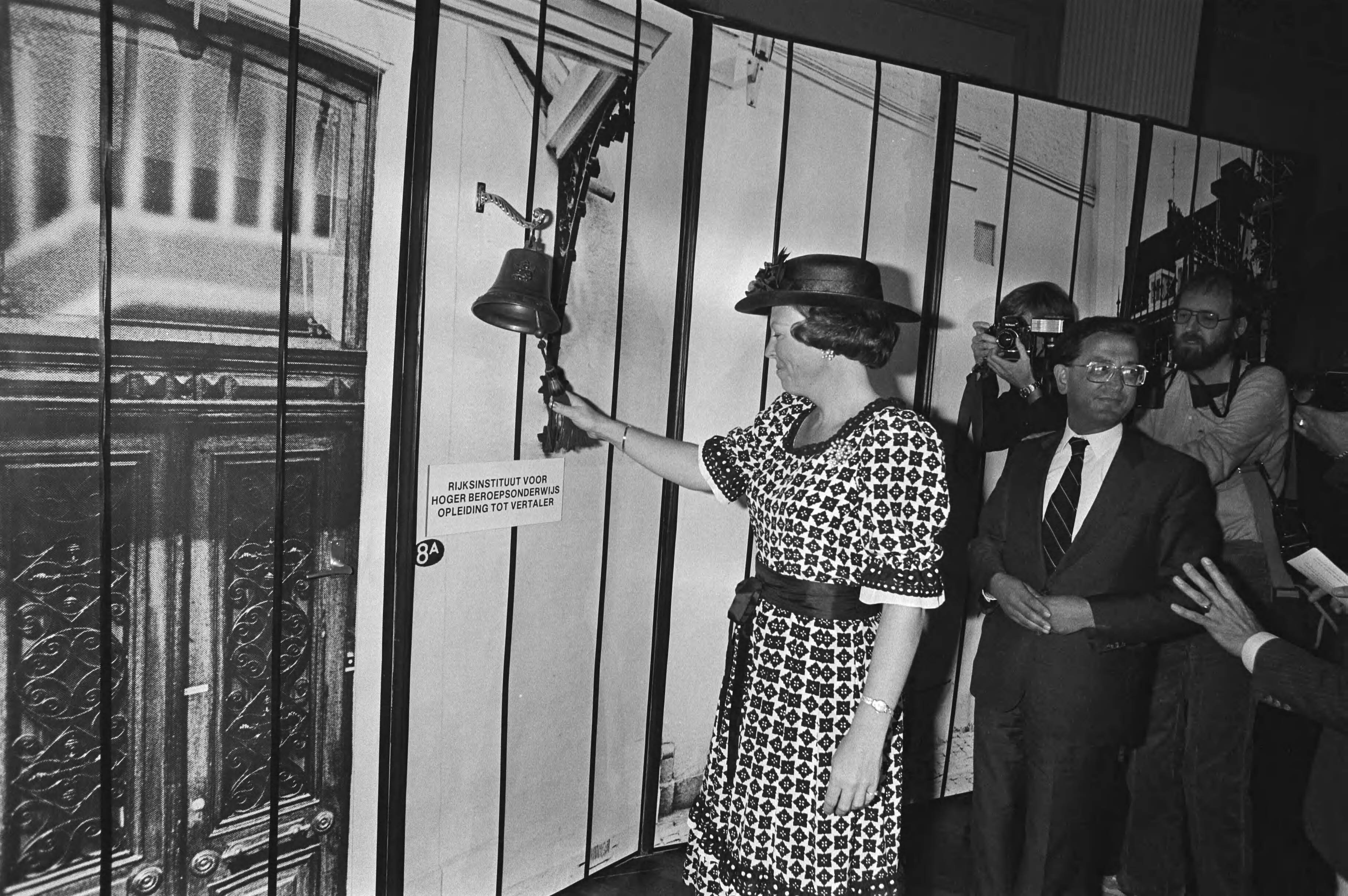Koningin Beatrix en prins Claus bezoeken Zuid-Limburg — De opening van het Rijksinstituut voor Hoger Beroeps Onderwijs, opleiding tot vertaler; koningin Beatrix luidt de bel; rechts minister Arie Pais van Onderwijs (VVD) — Foto: Croes, Rob C. / Anefo. Licentie: Set B: Rechtenvrij / Publiek Domein. Bron: Nationaal Archief. http://hdl.handle.net/10648/ad023220-d0b4-102d-bcf8-003048976d84