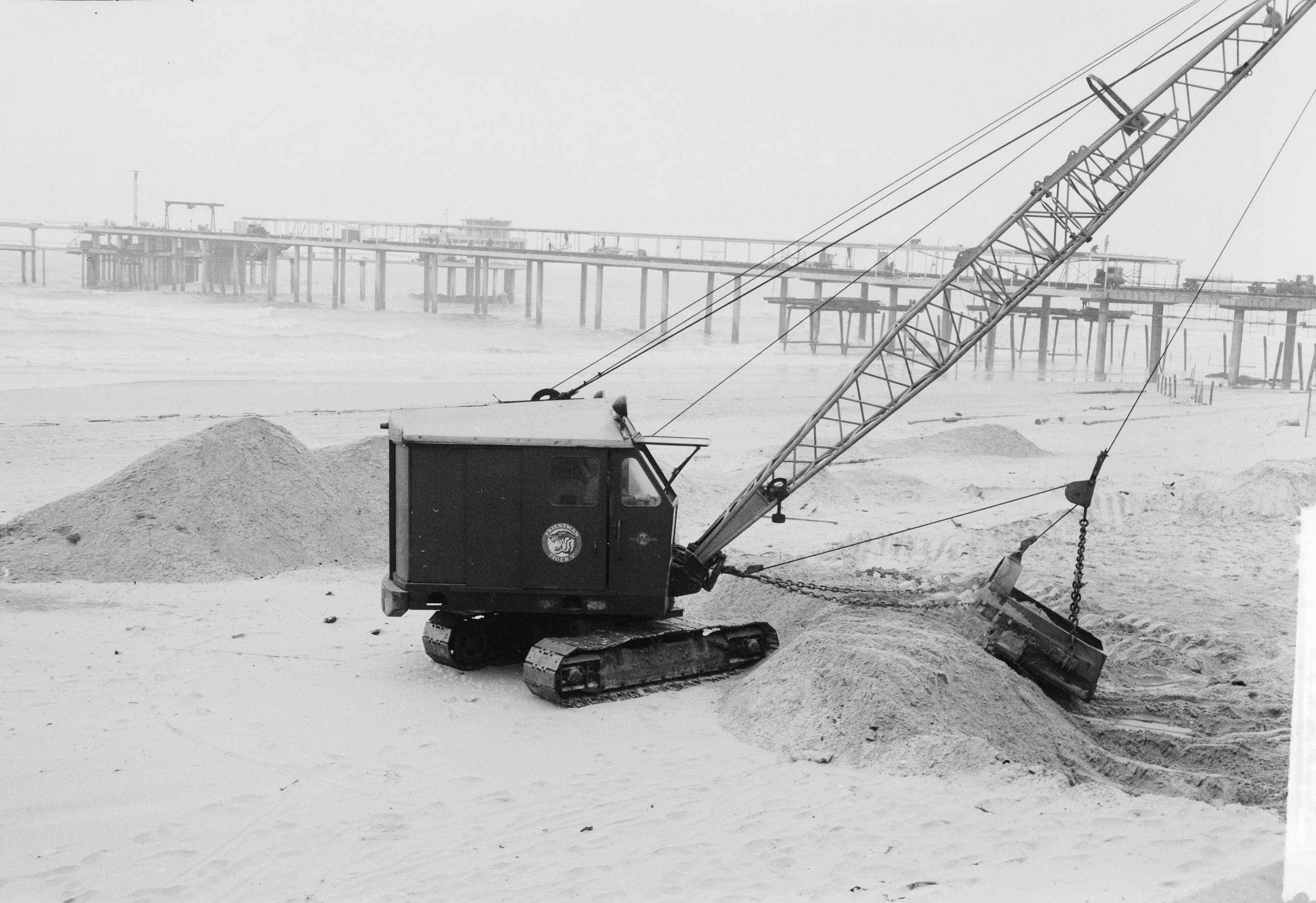 Fotocollectie Anefo — Egaliseren van het strand te Scheveningen voor het komend badseizoen — Foto: Behrens, Herbert F. / Anefo. Licentie: Set B: Rechtenvrij / Publiek Domein. Bron: Nationaal Archief. http://hdl.handle.net/10648/a9ccefc8-d0b4-102d-bcf8-003048976d84