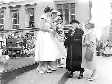 Fotocollectie Anefo — Receptie van de Haagse bloemenkoningin. Fenna de Eerste (de 26-jarige Fenna Betzema) samen met de bloemenprinsessen Sietske Wybenga en Toos Hooitsema. De oudste inwoonster van Den Haag mevr. Lamberts-Koopman (105 jaar) biedt bloemen aan — Foto: Noske, J.D. / Anefo. Licentie: Set B: Rechtenvrij / Publiek Domein. Bron: Nationaal Archief. http://hdl.handle.net/10648/a966dfc6-d0b4-102d-bcf8-003048976d84
