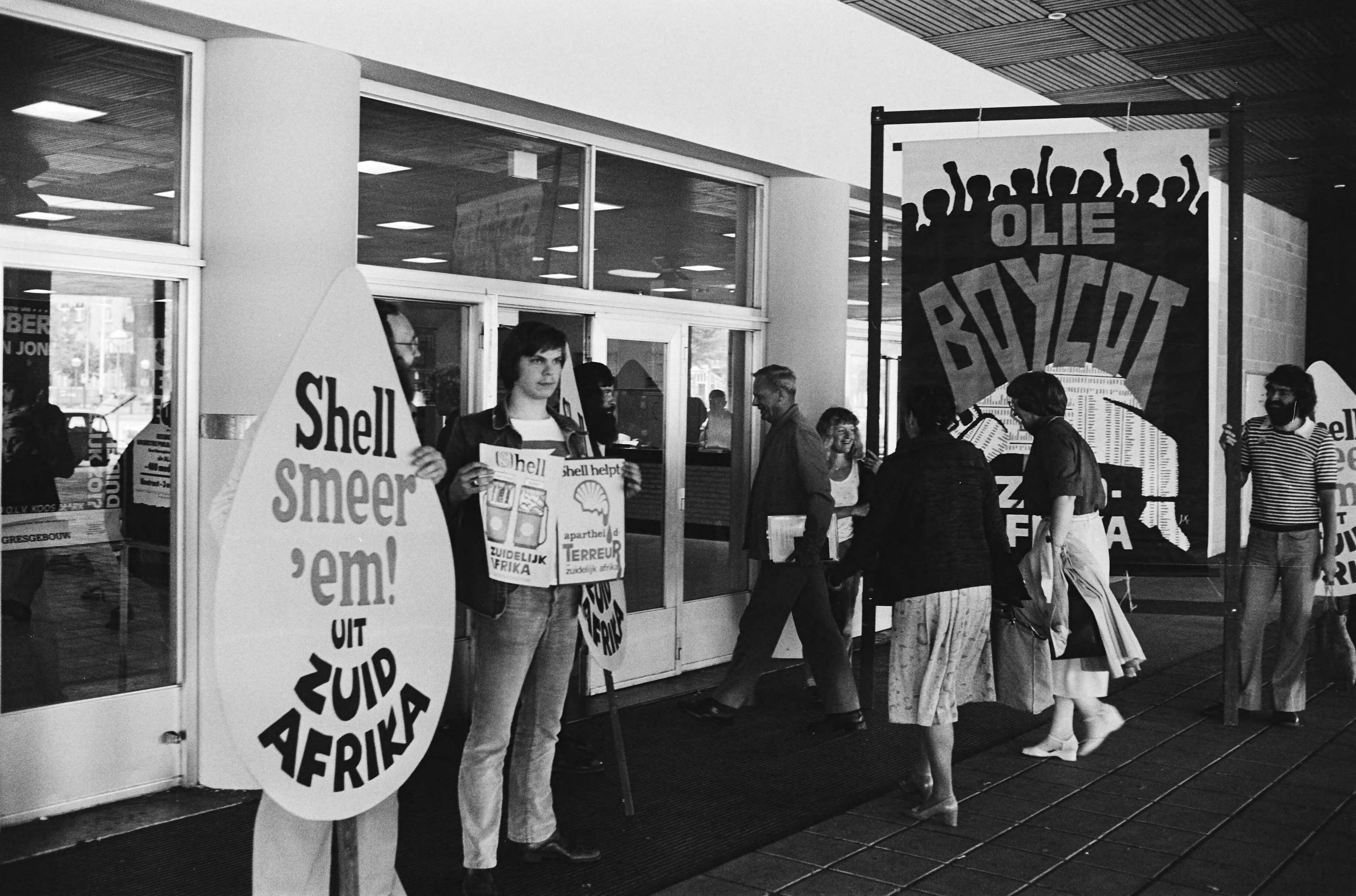 Fotocollectie Anefo — Shell aandeelhoudersvergadering in Congresgebouw in Den Haag ; demonstranten bij de ingang — Foto: Suyk, Koen / Anefo. Licentie: Set B: Rechtenvrij / Publiek Domein. Bron: Nationaal Archief. http://hdl.handle.net/10648/ace0bece-d0b4-102d-bcf8-003048976d84
