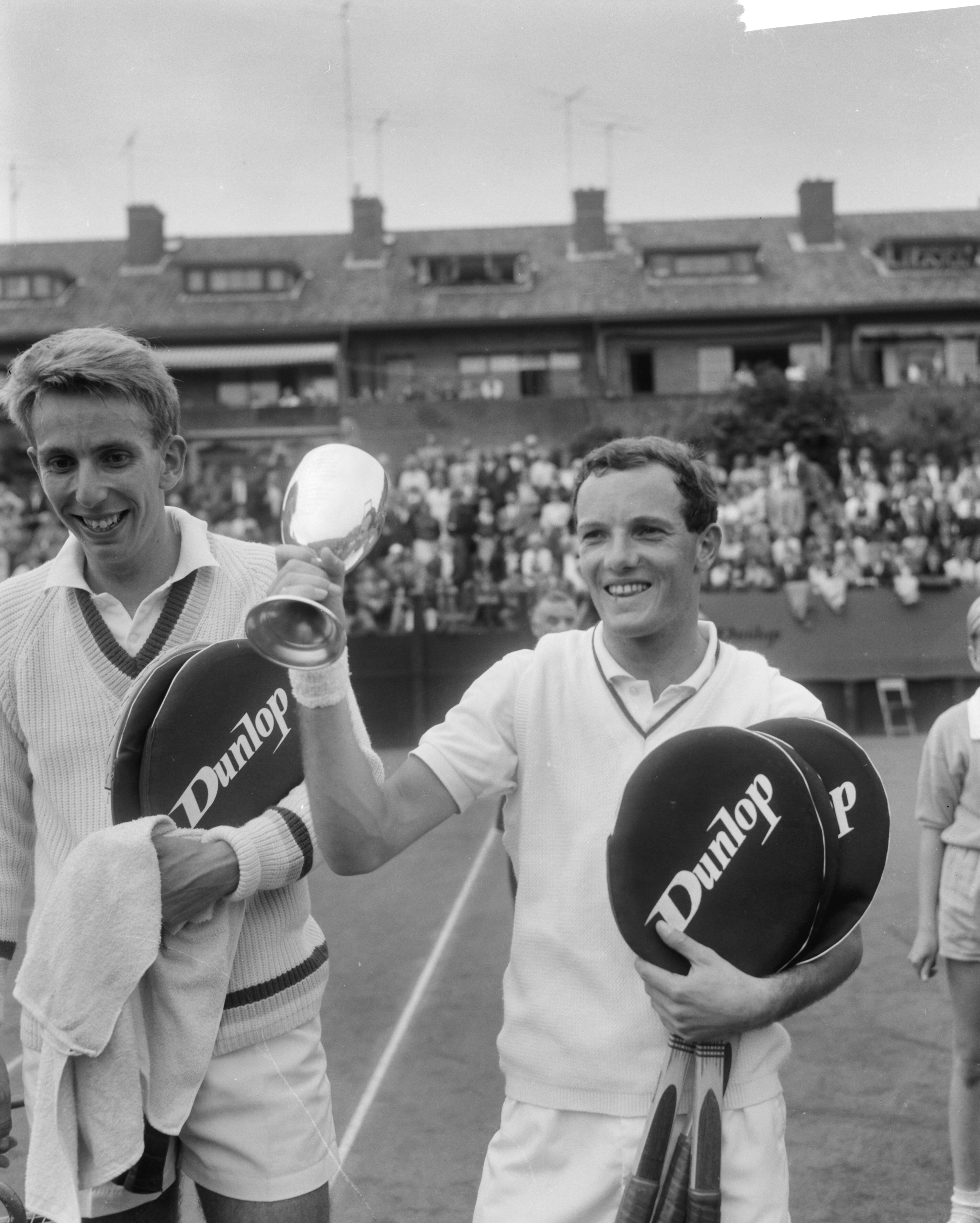 Fotocollectie Anefo — Nederlandse tenniskampioenschappen op de METS-banen te Scheveningen, finale herenenkel, winnaar Tom Okker (rechts), met beker en zijn tegenstander Evert Schneider — Foto: Bilsen, Joop van / Anefo. Licentie: Set B: Rechtenvrij / Publiek Domein. Bron: Nationaal Archief. http://hdl.handle.net/10648/aabb44b6-d0b4-102d-bcf8-003048976d84