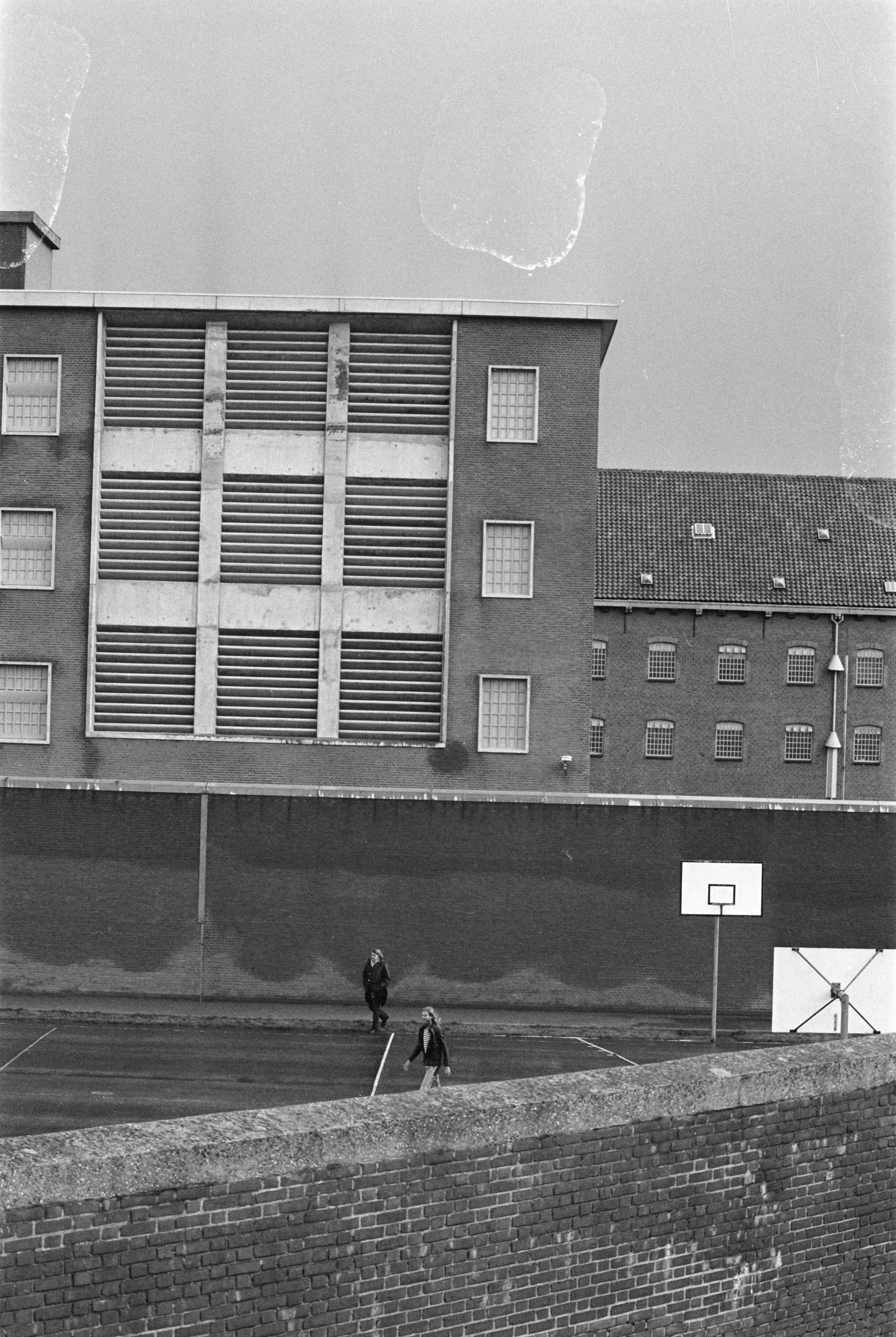 Fotocollectie Anefo — Gijzeling in Scheveningen; het gebouw waar zich (rechts onder) het gijzelingsdrama afspeelt, op de voorgrond beoefenen andere gedetineerden sport — Foto: Mieremet, Rob / Anefo. Licentie: Set B: Rechtenvrij / Publiek Domein. Bron: Nationaal Archief. http://hdl.handle.net/10648/ac591bb8-d0b4-102d-bcf8-003048976d84