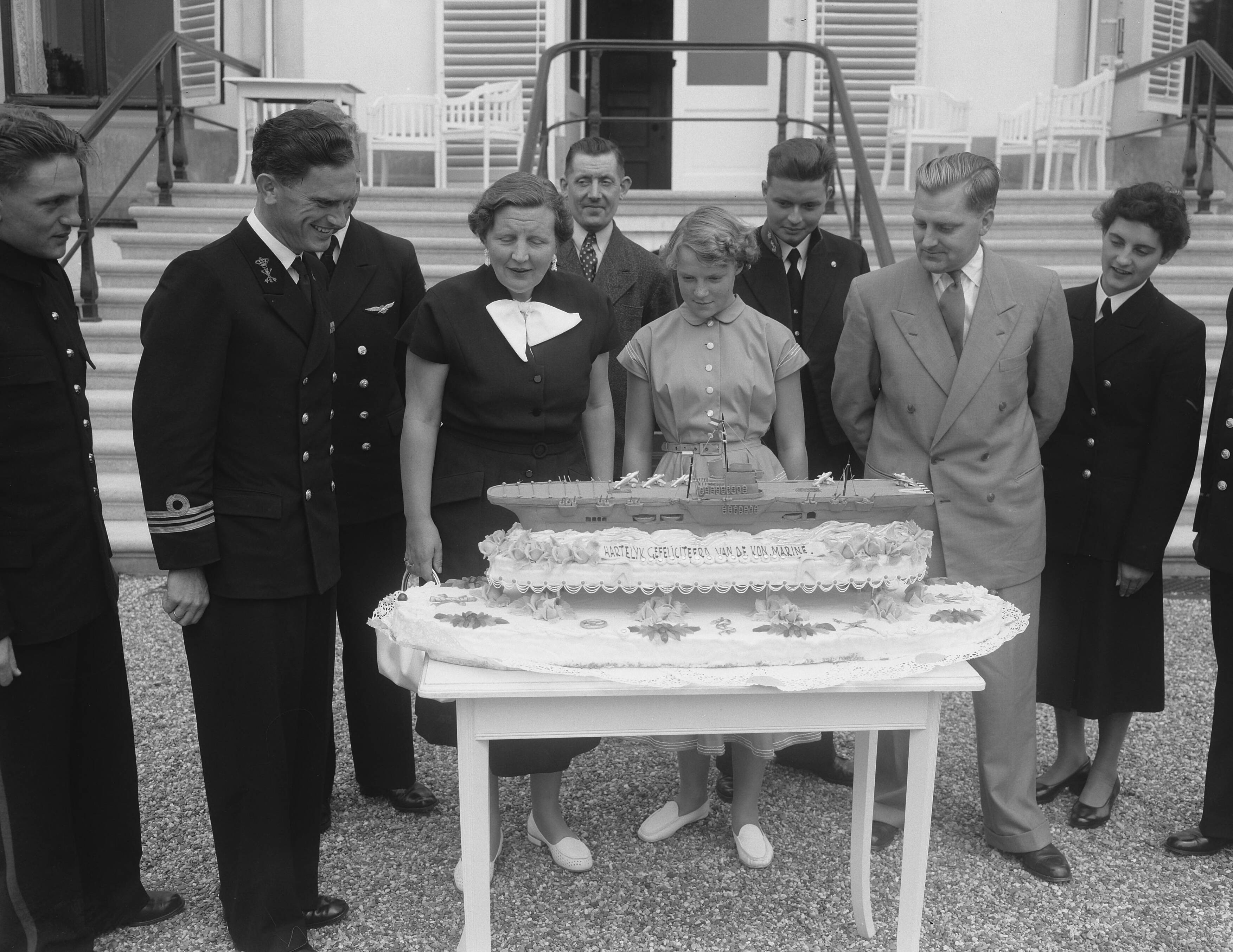 Fotocollectie Anefo — Aanbieding geschenken aan jarige prinses Irene op Soestdijk. Een deputatie van de Koninklijke Marine bood een taart aan, met een model van het vliegdekschip "Karel Doorman. Links de luitenant-ter-zeer 1e klasse J.L. Tuinman. Rechts de maker van het model de heer Helders — Foto: Noske, J.D. / Anefo. Licentie: Set B: Rechtenvrij / Publiek Domein. Bron: Nationaal Archief. http://hdl.handle.net/10648/a9275ce8-d0b4-102d-bcf8-003048976d84