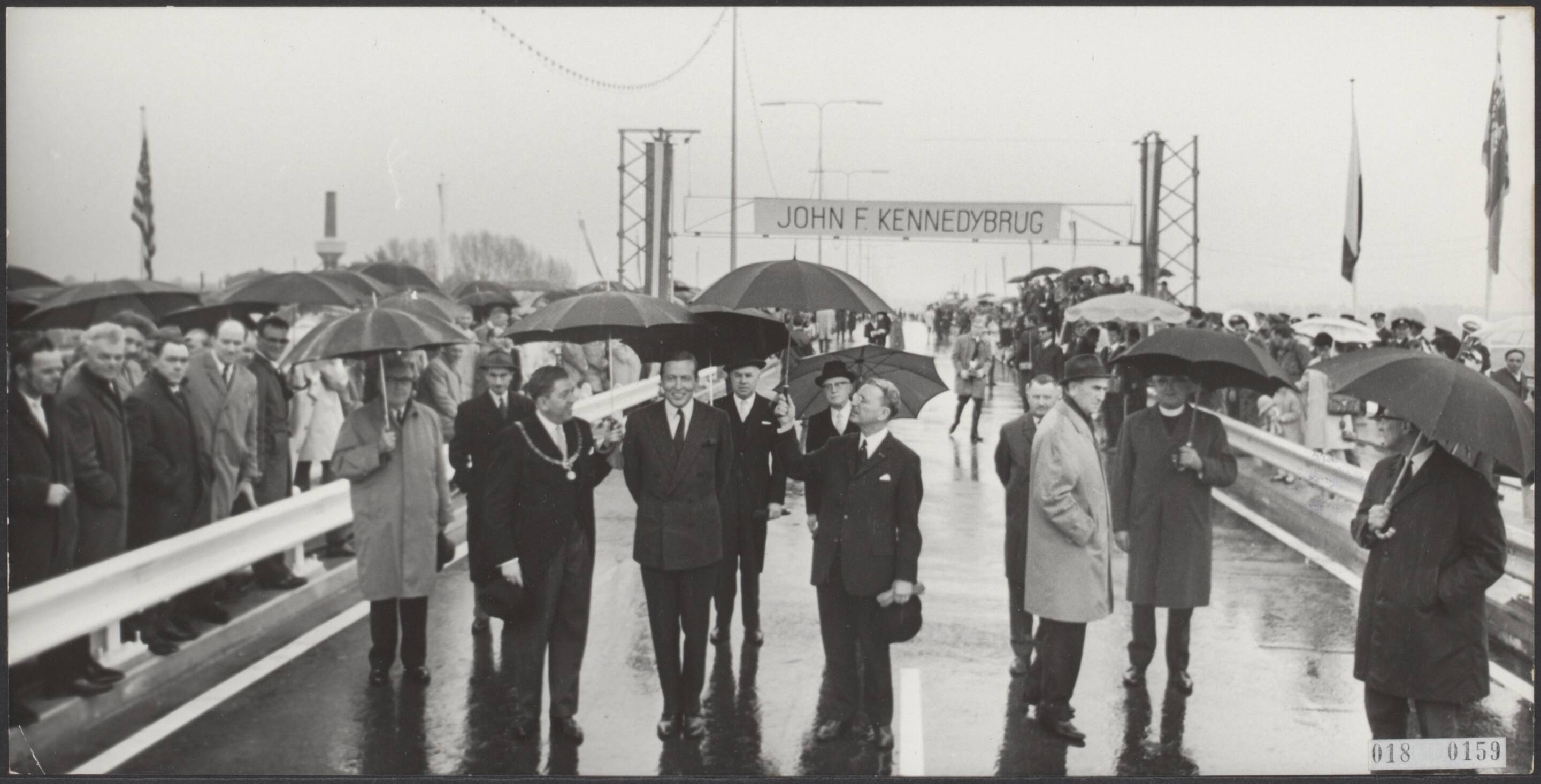 Fotocollectie Elsevier Binnenland — Prins Claus heeft de officiële opening verricht van de John F. Kennedybrug over de Maas te Maastricht. Na de opening wandelde de prins, vergezeld van de burgemeester van Maastricht, A.M.I.H. Baeten, en de Commissaris van de Koningin, mr. Ch. J.M.A. van Rooy naar de gereedstaande auto om als eerste over de nieuwe brug te gaan — Foto: Nijs, Jac. de / Anefo. Licentie: Set B: Rechtenvrij / Publiek Domein. Bron: Nationaal Archief. http://hdl.handle.net/10648/adc165fa-d0b4-102d-bcf8-003048976d84