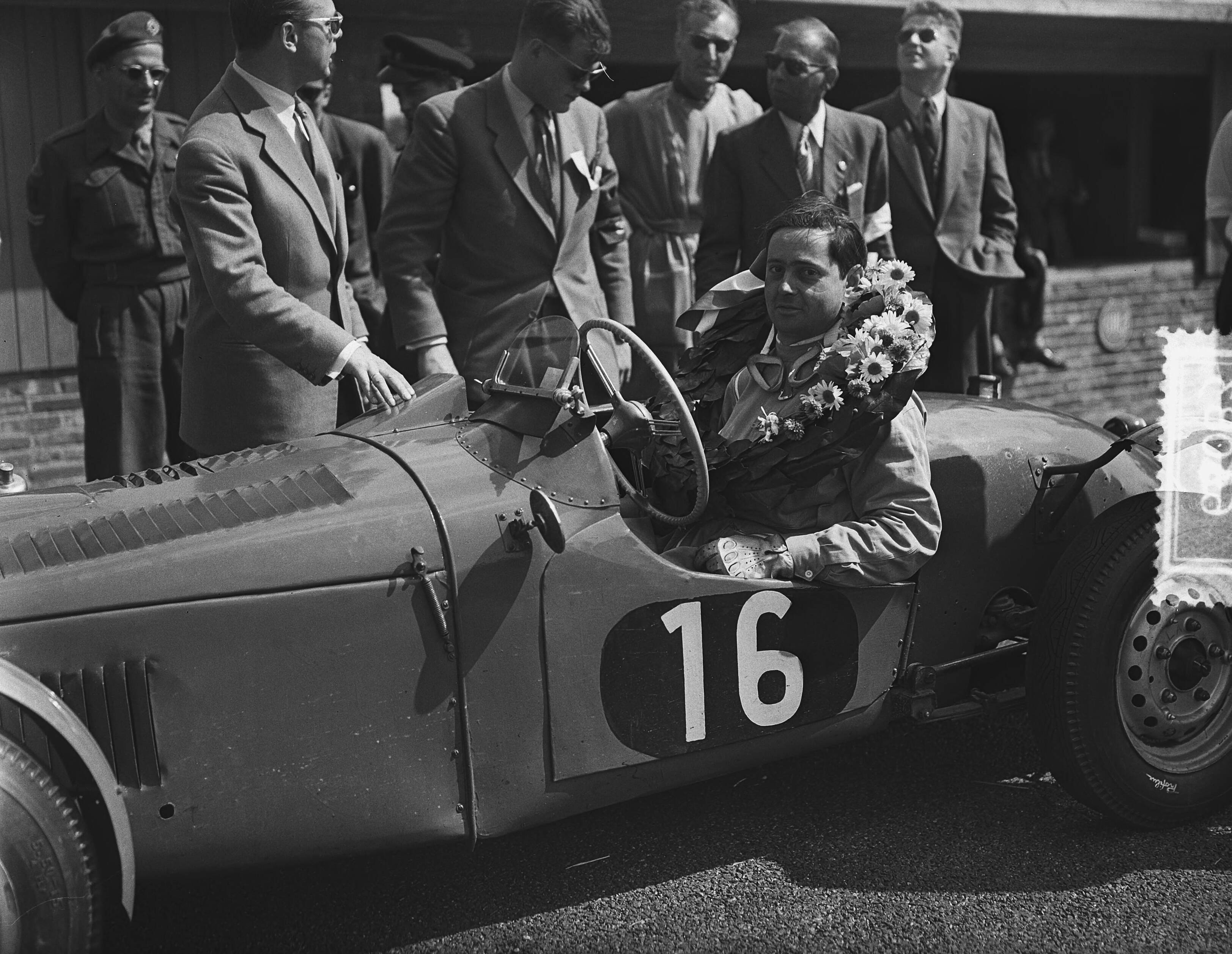 Fotocollectie Anefo — Nationale Sportwagenraces op het circuit van Zandvoort. Winnaar met krans — Foto: Bilsen, Joop van / Anefo. Licentie: Set B: Rechtenvrij / Publiek Domein. Bron: Nationaal Archief. http://hdl.handle.net/10648/a9233d0c-d0b4-102d-bcf8-003048976d84