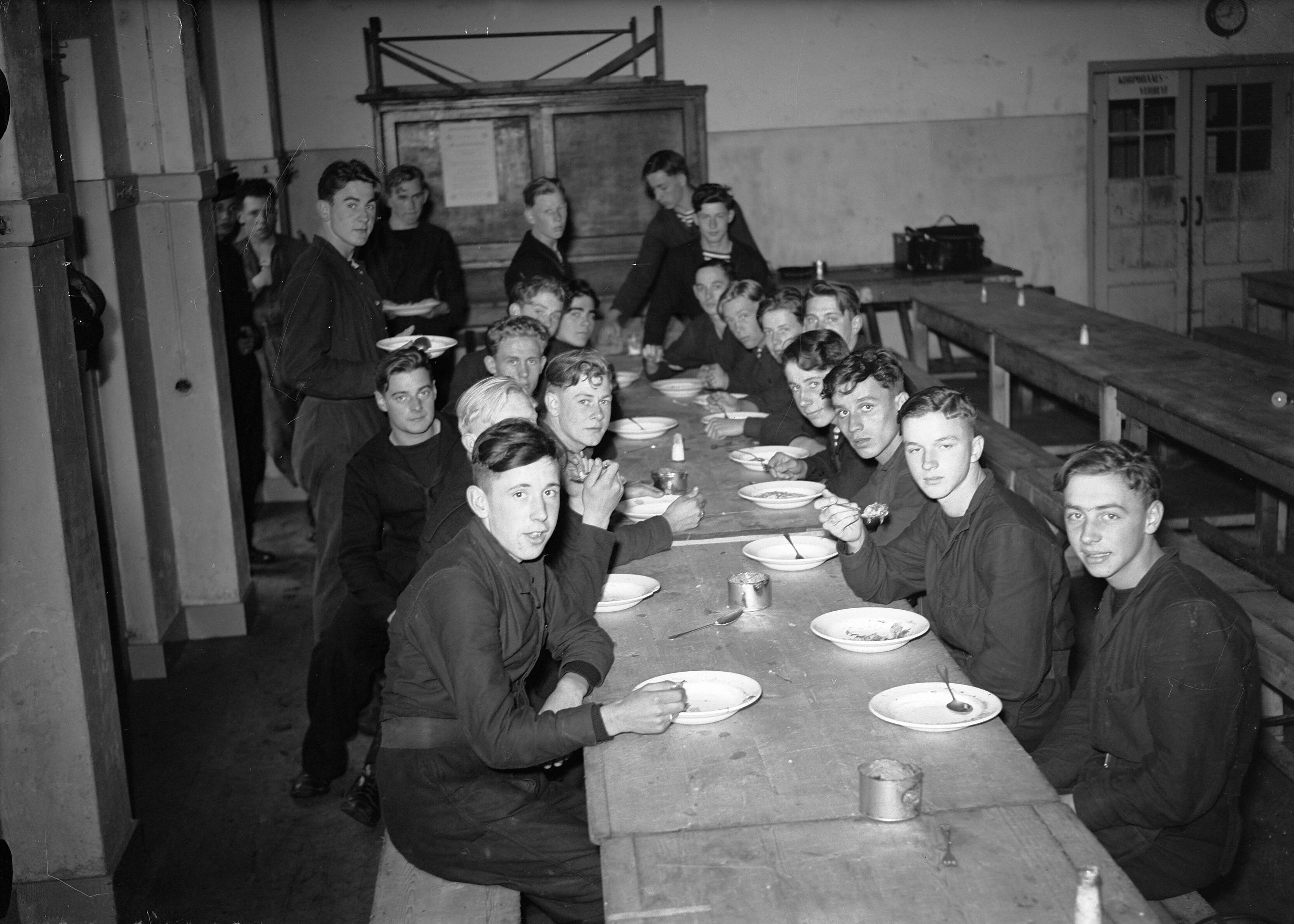 Fotocollectie Anefo — MOK Hilversum. Matrozen aan het eten — Foto: Steenkamp, […] / Anefo. Licentie: Set B: Rechtenvrij / Publiek Domein. Bron: Nationaal Archief. http://hdl.handle.net/10648/a8bd8d68-d0b4-102d-bcf8-003048976d84