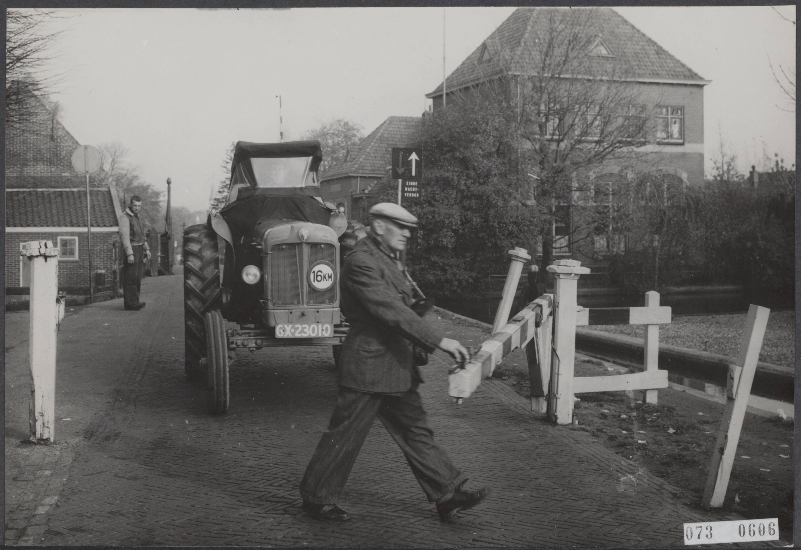 Fotocollectie Elsevier Binnenland — De tol in Leimuiden bij Alphen a/d Rijn gaat op 14 november 1953 verdwijnen. De tol bevindt zich in de Dorpsstraat en dateert uit het jaar 1878. Toldhouder De Koning opent bijna voor de laatste keer de tolboom. Er blijft echter in Leimuiden nog een tol bestaan, nl. aan de Bilderdam waar als tolhouder L. Penning optreedt — Foto: Fotograaf Onbekend / Anefo. Licentie: Set B: Rechtenvrij / Publiek Domein. Bron: Nationaal Archief. http://hdl.handle.net/10648/ae151a60-d0b4-102d-bcf8-003048976d84