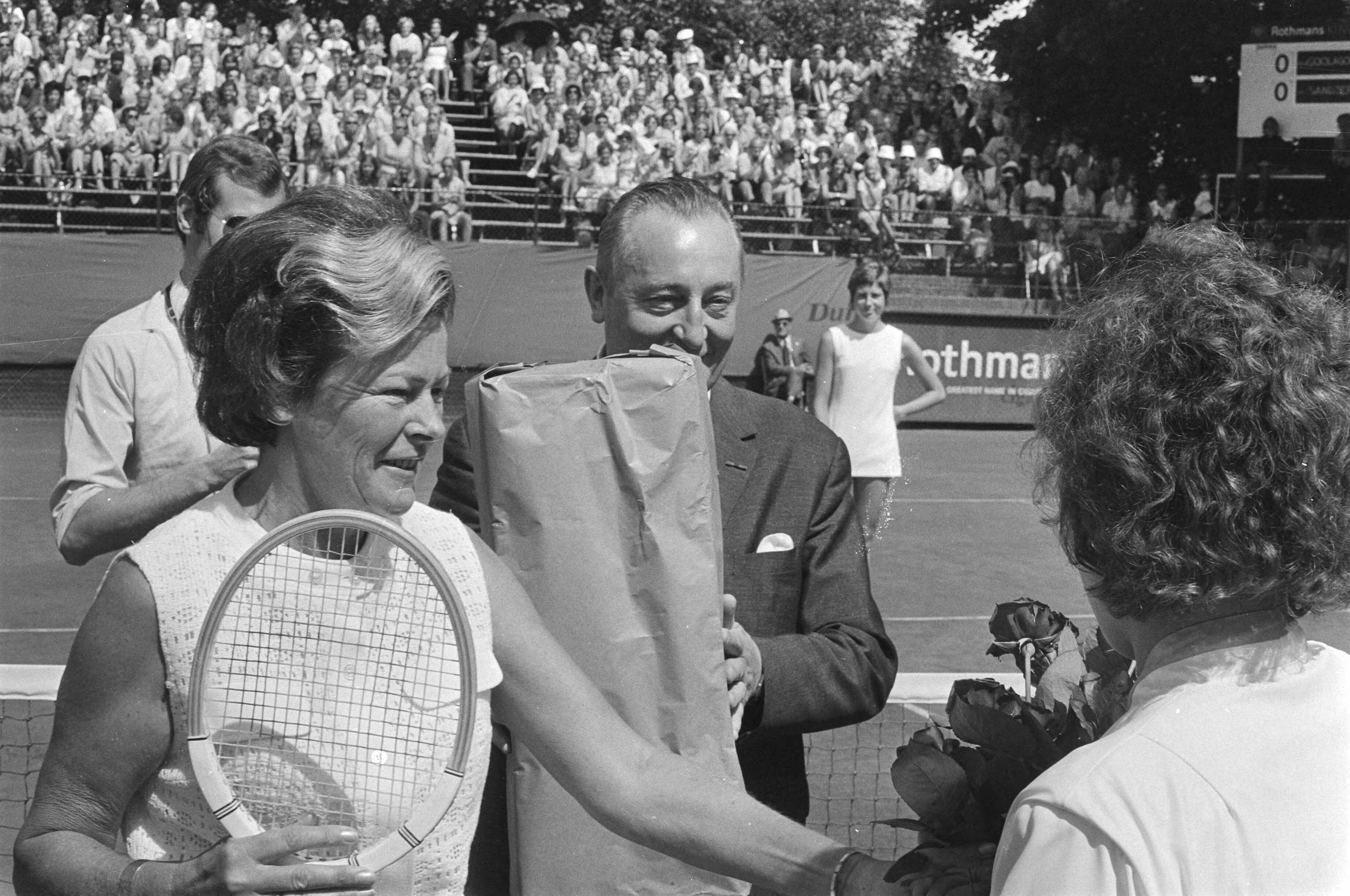 Fotocollectie Anefo — Internationale tenniskampioenschappen te Hilversum. Winnares Evonne Goolagong wordt met haar verjaardag gefeliciteerd door toernooidirecteur Jan Mulder en secretaris Scholtze — Foto: Punt, W. / Anefo. Licentie: Set B: Rechtenvrij / Publiek Domein. Bron: Nationaal Archief. http://hdl.handle.net/10648/abc870d6-d0b4-102d-bcf8-003048976d84