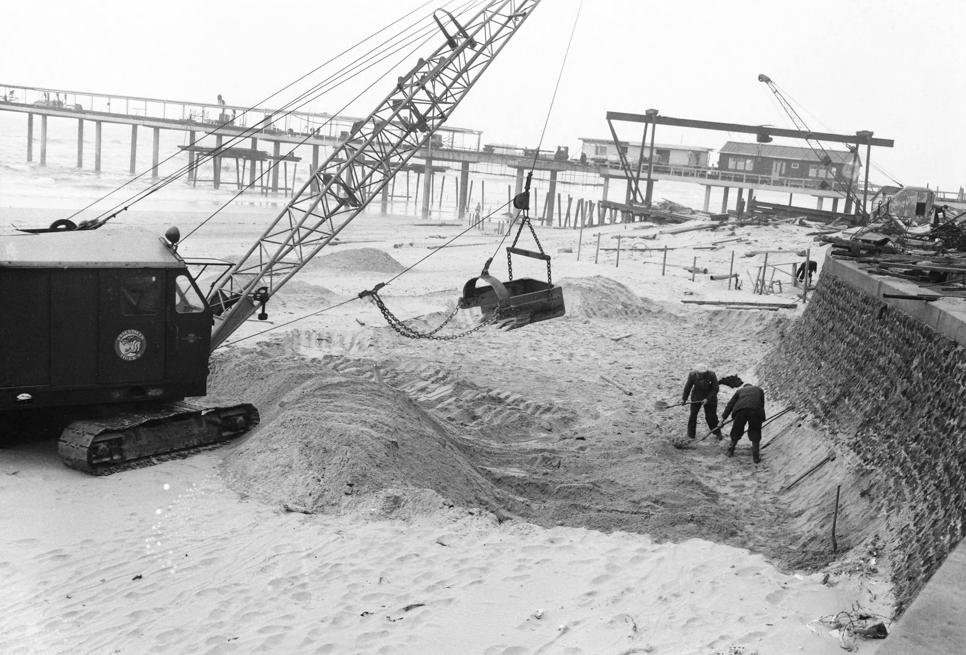 Fotocollectie Anefo — Egaliseren van het strand te Scheveningen voor het komend badseizoen — Foto: Behrens, Herbert F. / Anefo. Licentie: Set B: Rechtenvrij / Publiek Domein. Bron: Nationaal Archief. http://hdl.handle.net/10648/a9ccf374-d0b4-102d-bcf8-003048976d84