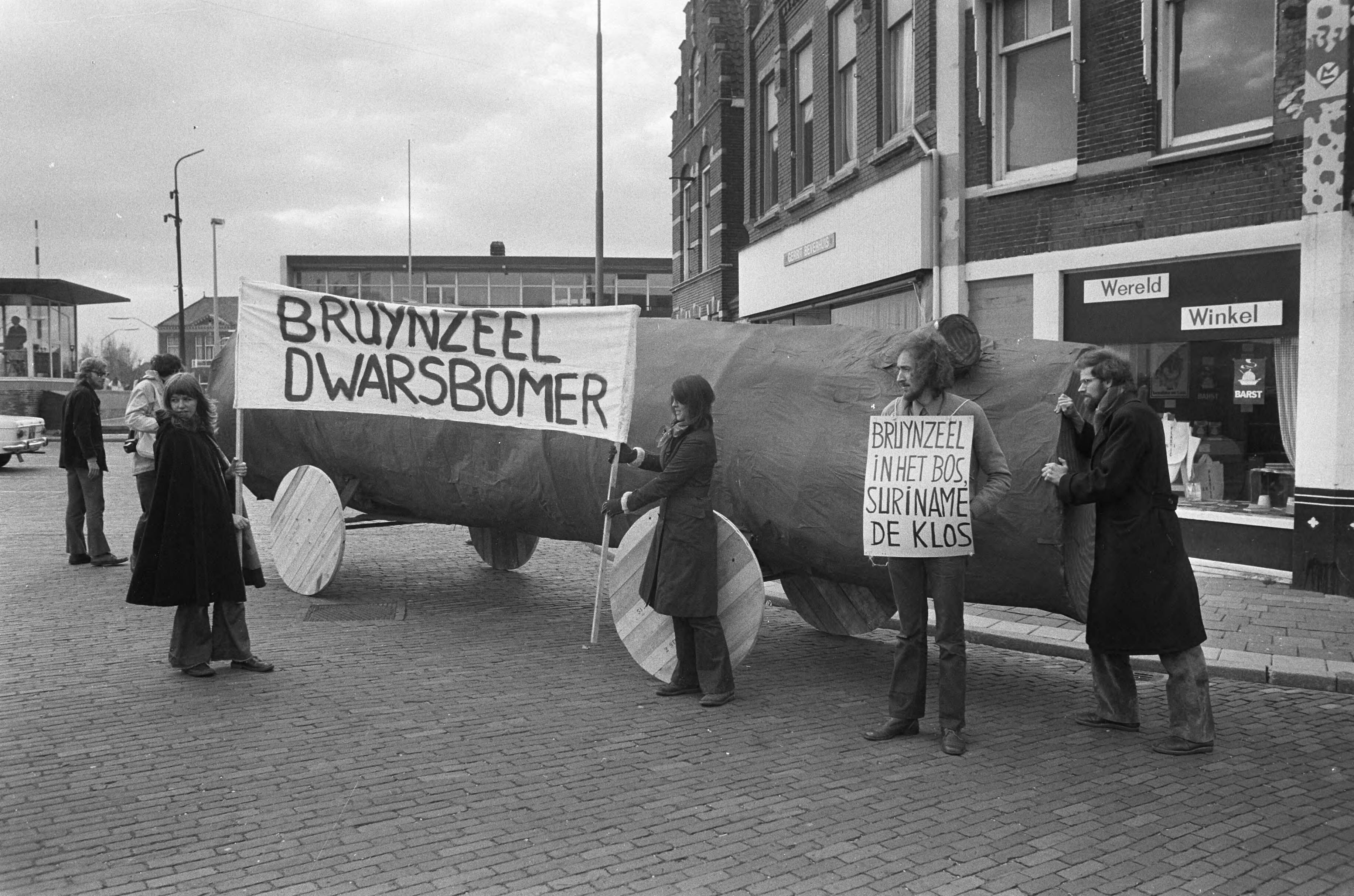Fotocollectie Anefo — Jongeren demonstreren met een kartonnen boom tegen het gebruik van ontwikkelingsgelden voor de bouw van een fabriek van Bruynzeel in Suriname — Foto: Peters, Hans / Anefo. Licentie: Set B: Rechtenvrij / Publiek Domein. Bron: Nationaal Archief. http://hdl.handle.net/10648/ac3c990c-d0b4-102d-bcf8-003048976d84