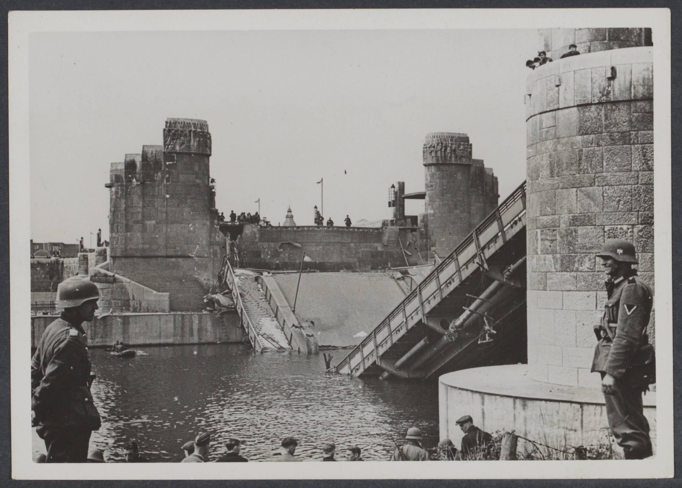 B. Nederlands Front - Meidagen '40. — Duitse troepen steken de Maas in Maastricht over op rubberboten. Rechts de opgeblazen Wilhelminabrug — Foto: Dietz / Kriegsberichter. Licentie: Set B: Rechtenvrij / Publiek Domein. Bron: Nationaal Archief. http://hdl.handle.net/10648/f8fb92fe-ac8a-b53c-ca3a-67d3e9d26869