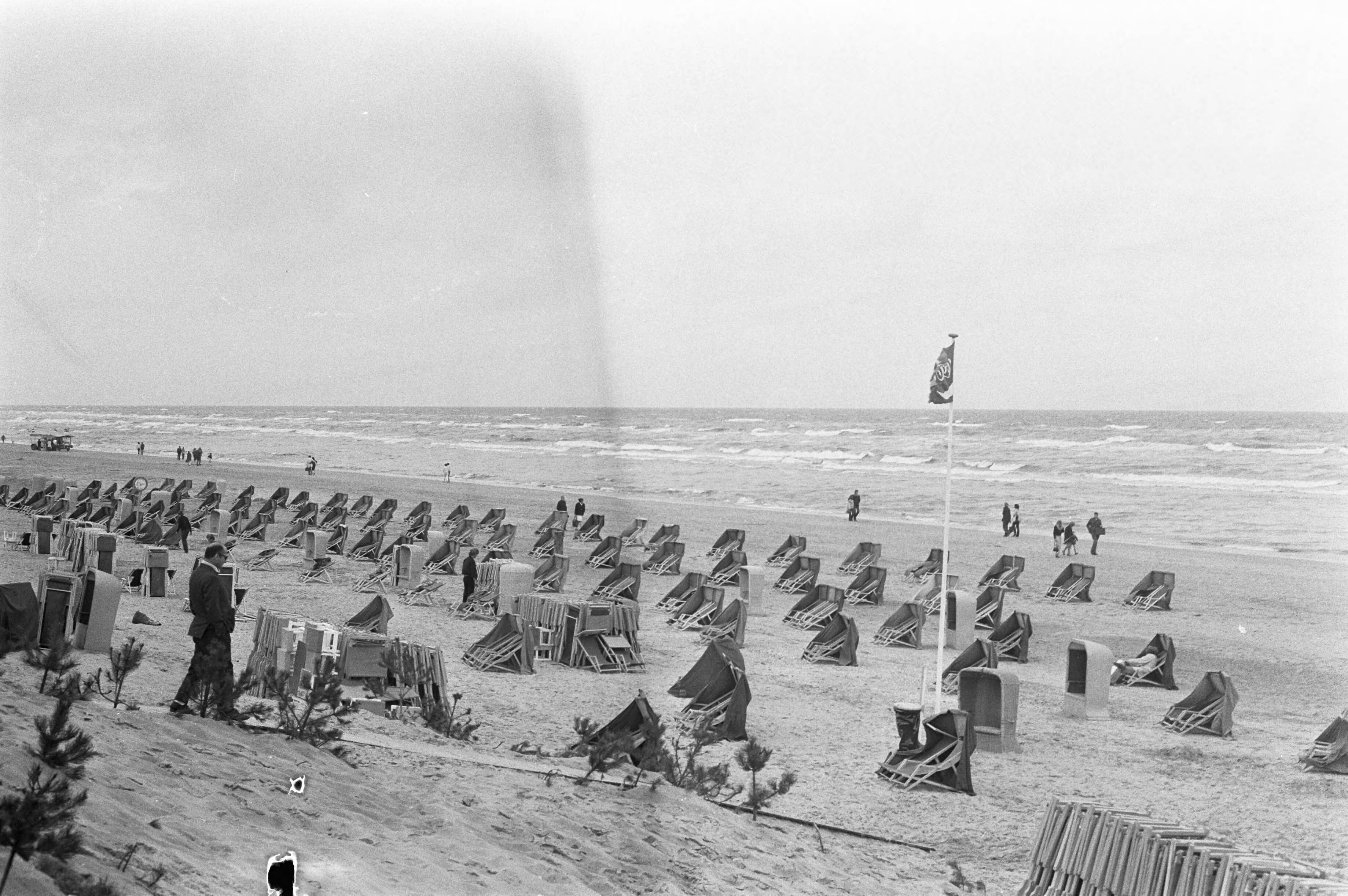 Fotocollectie Anefo — Mensen met paraplu op het strand van Zandvoort, strand met lege stoelen ivm guur weer — Foto: Peters, Hans / Anefo. Licentie: Set B: Rechtenvrij / Publiek Domein. Bron: Nationaal Archief. http://hdl.handle.net/10648/abee657a-d0b4-102d-bcf8-003048976d84