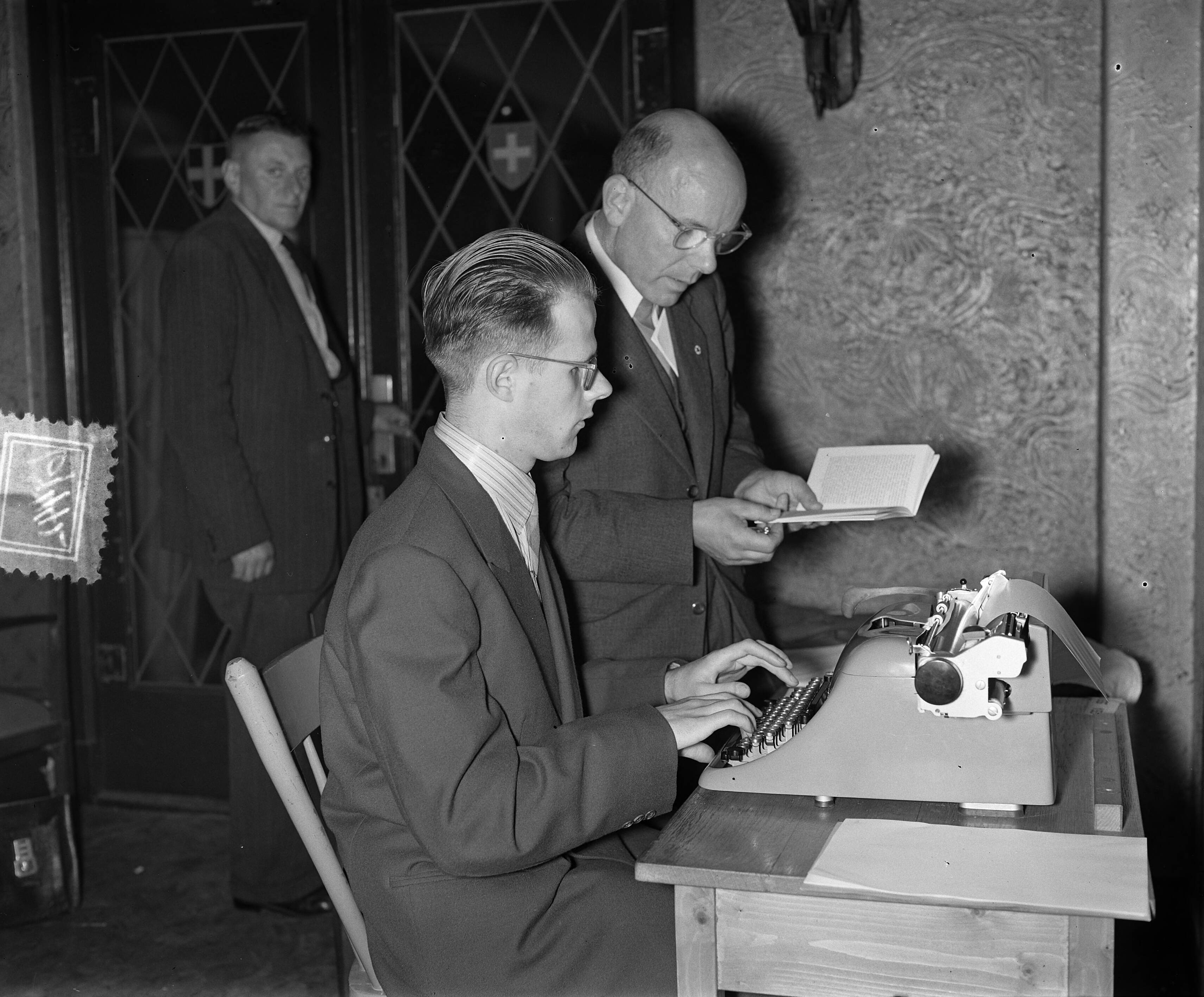Fotocollectie Anefo — Nationale kampioenschap typen in Den Haag. Een blinde typist wordt voorgelezen — Foto: Rossem, Wim van / Anefo. Licentie: Set B: Rechtenvrij / Publiek Domein. Bron: Nationaal Archief. http://hdl.handle.net/10648/a92a2194-d0b4-102d-bcf8-003048976d84