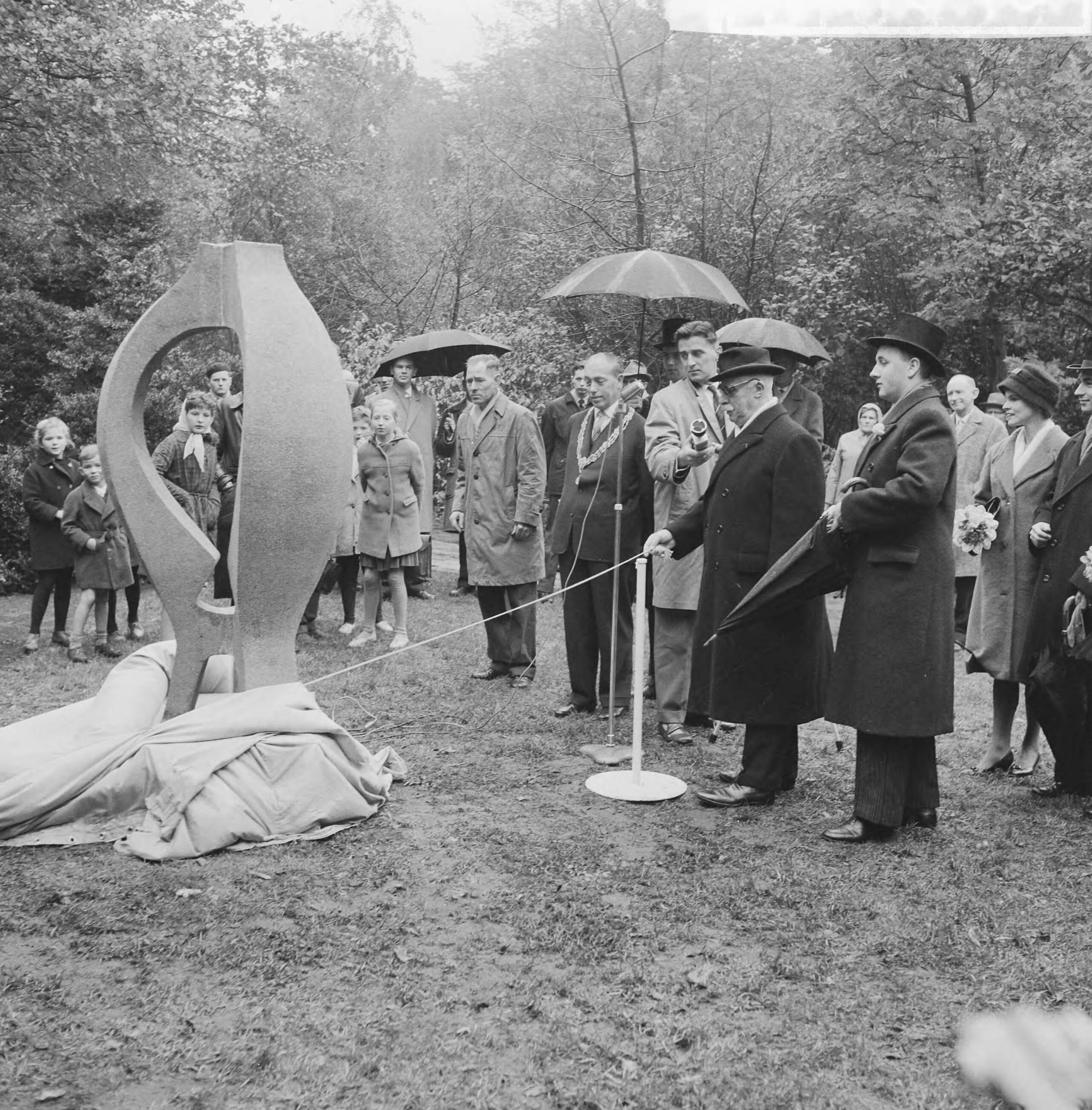 Fotocollectie Anefo — Onthulling monument door jhr. I.L. van den Berch van Heemstede in de tuin van het paleis Noordeinde te Den Haag, ter herinnering aan de eerste ballonvlucht in Nederland. Links, met ambtsketen, wethouder D.W. Dettmeijer. Rechts K.H. Ledeboer, voorzitter van de vliegtuigbouwkundige studievereniging "Leonardo da Vinci" — Foto: Behrens, Herbert F. / Anefo. Licentie: Set B: Rechtenvrij / Publiek Domein. Bron: Nationaal Archief. http://hdl.handle.net/10648/a9bc5708-d0b4-102d-bcf8-003048976d84