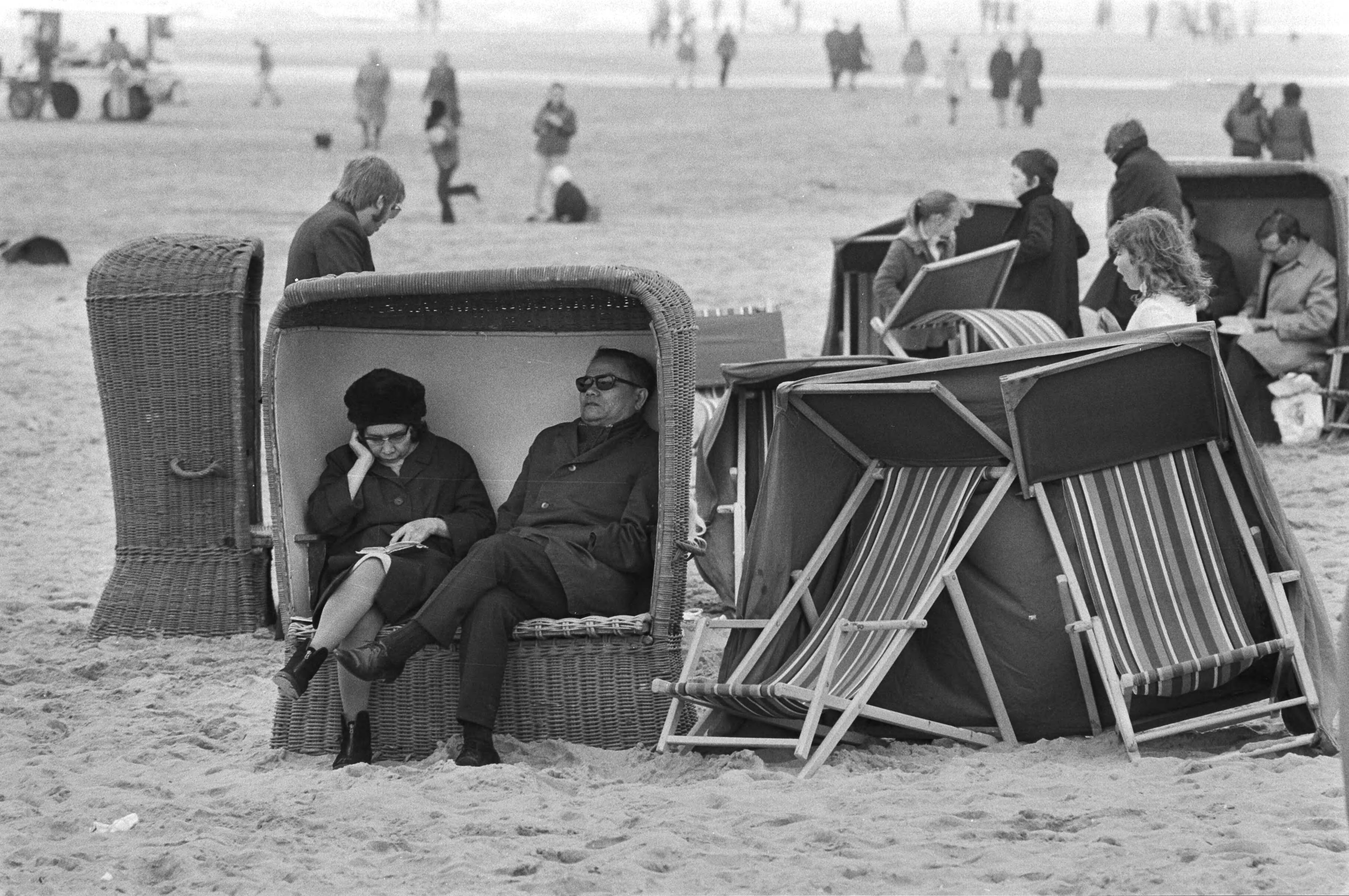 Zandvoort — Mensen in dikke kleding in een strandstoel — Foto: Fotograaf Onbekend / Anefo. Licentie: Set B: Rechtenvrij / Publiek Domein. Bron: Nationaal Archief. http://hdl.handle.net/10648/abbaf208-d0b4-102d-bcf8-003048976d84