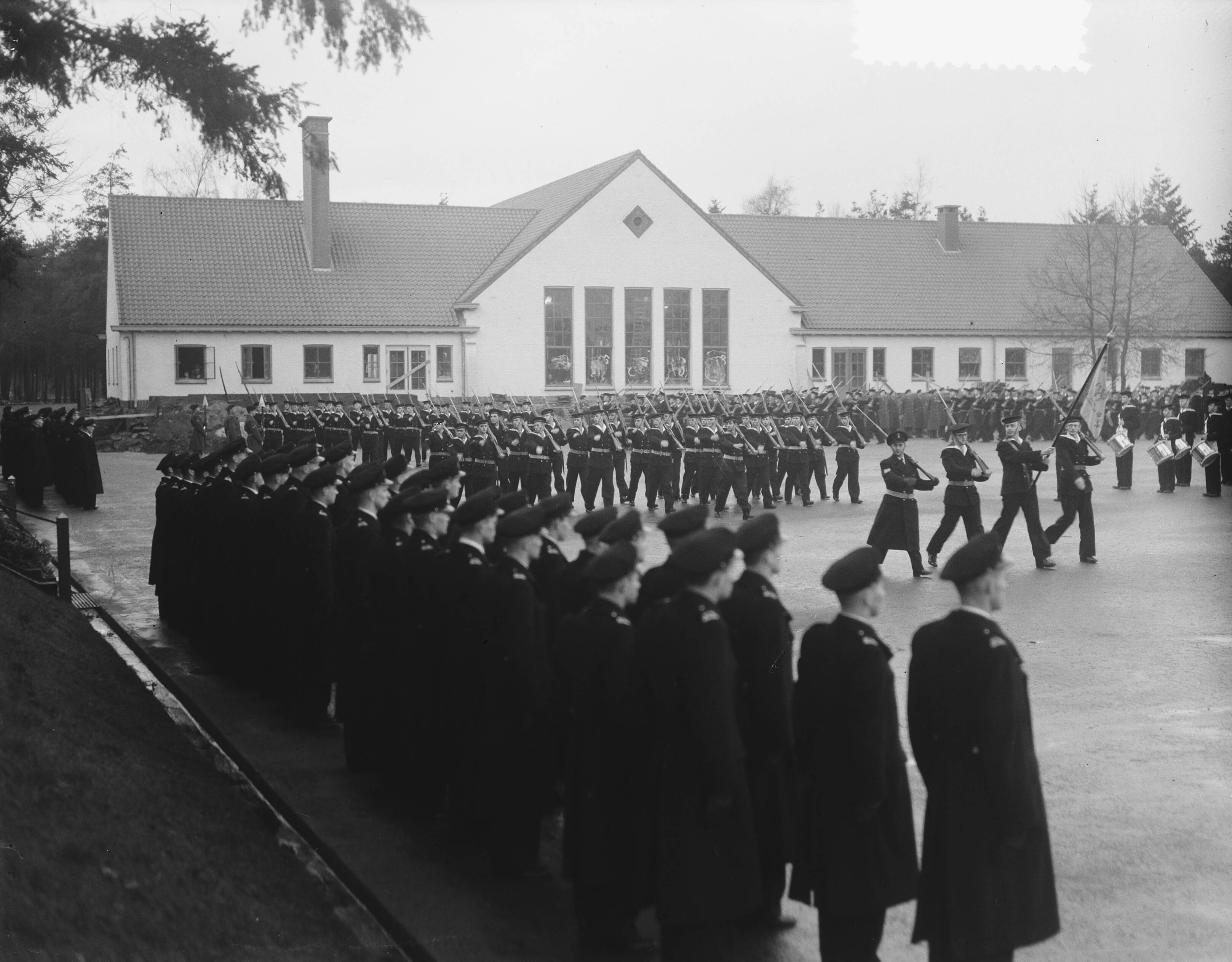 Beëdiging van 37 marine-officieren in MOK HIlversum — In het Marine-opleidingskamp nabij Hilversum zijn 37 marineofficieren beëdigd door de kapitein-ter-zee ]. J. Hogendoorn — Foto: Bilsen, Joop van / Anefo. Licentie: Set B: Rechtenvrij / Publiek Domein. Bron: Nationaal Archief. http://hdl.handle.net/10648/a8f3fdda-d0b4-102d-bcf8-003048976d84