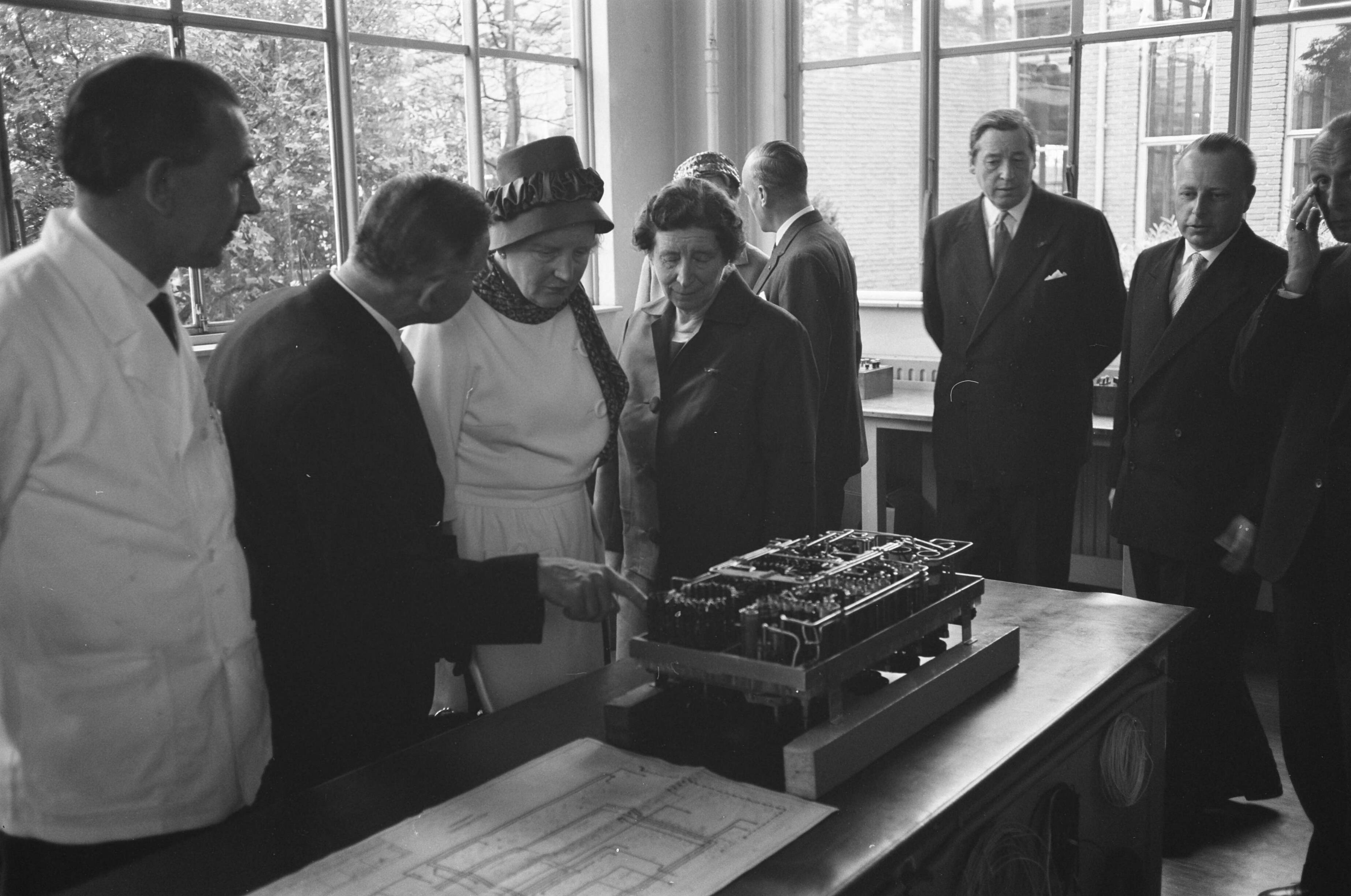 Bezoek koningin Juliana aan Zeist en omgeving — Bezoek koningin Juliana aan Zeist en omgeving. Koningin Juliana bezoekt de Nederlandsche Optiek- en Instrumentenfabriek Dr. C. Bleeker N.V. (Nedoptifa) in Zeist. Links van haar directeur G. Willemse, rechts oprichtster mej. dr. C.E. Bleeker — Foto: Pot, Harry / Anefo. Licentie: Set B: Rechtenvrij / Publiek Domein. Bron: Nationaal Archief. http://hdl.handle.net/10648/a9d73cd0-d0b4-102d-bcf8-003048976d84