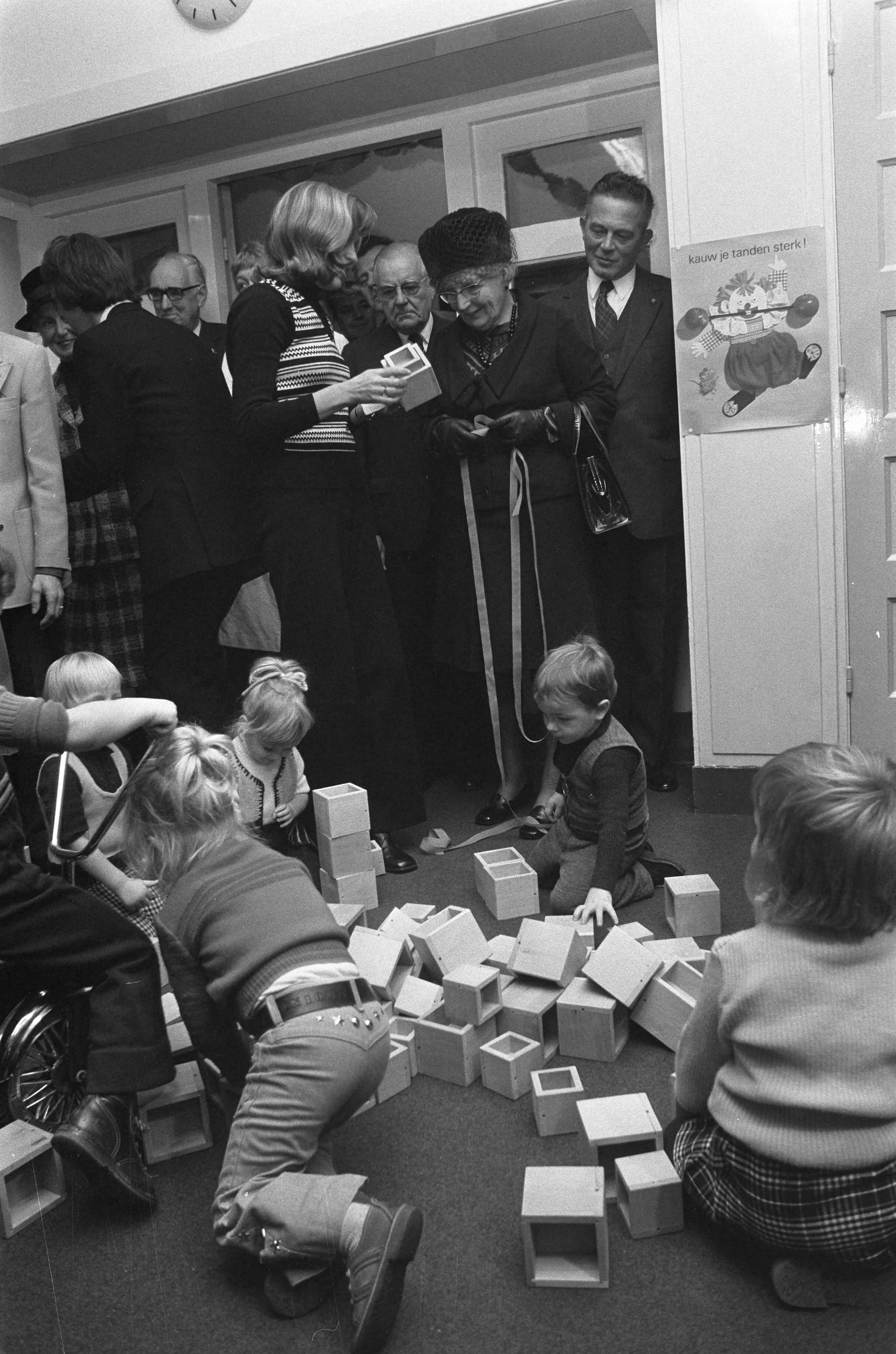 Koningin Juliana bezoekt scholen in Den Haag — De koningin bekijkt een project van de kinderen in een peuterspeelzaal — Foto: Fotograaf Onbekend / Anefo. Licentie: Set B: Rechtenvrij / Publiek Domein. Bron: Nationaal Archief. http://hdl.handle.net/10648/ac3c3fe8-d0b4-102d-bcf8-003048976d84