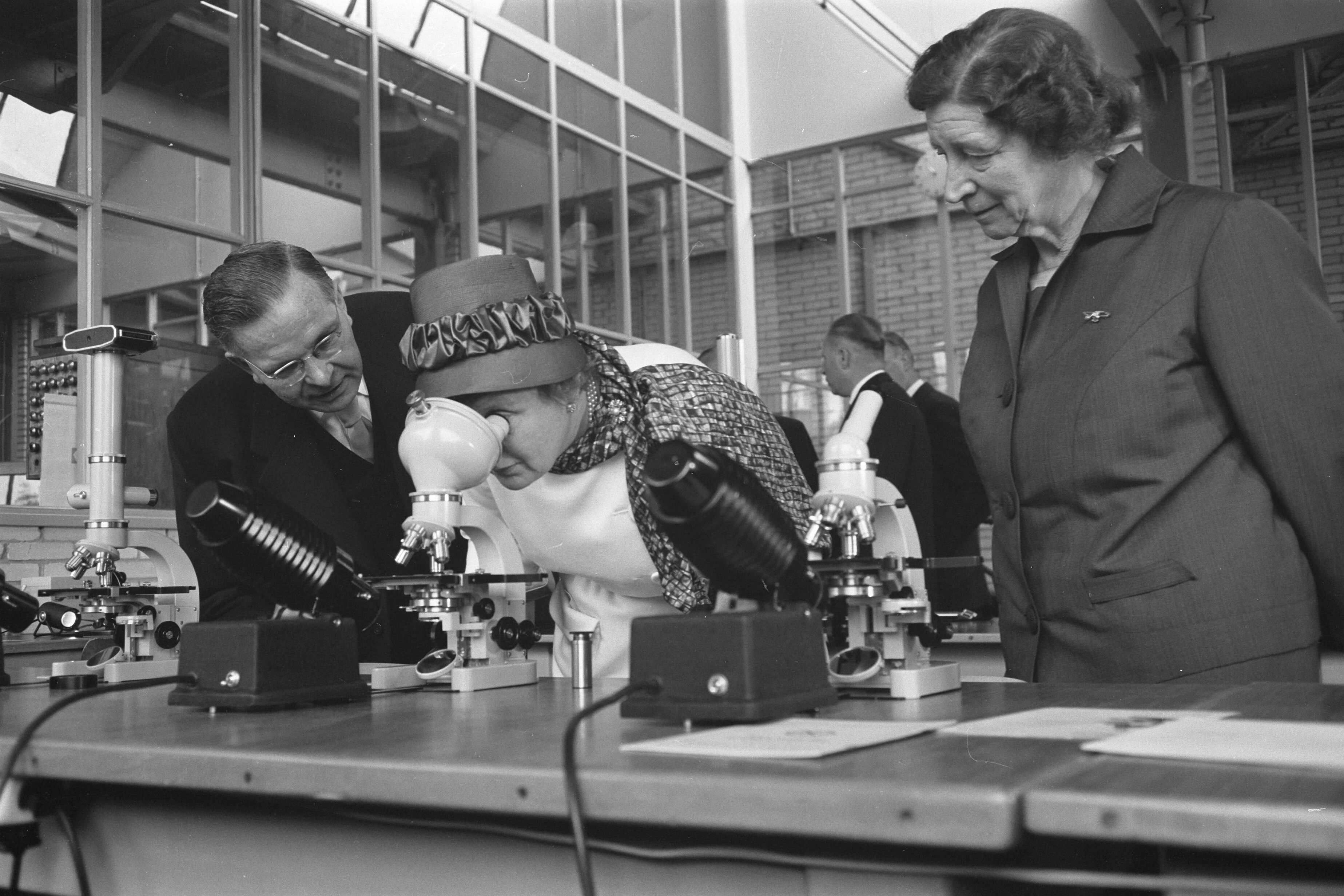 Bezoek koningin Juliana aan Zeist en omgeving — Bezoek koningin Juliana aan Zeist en omgeving. Koningin Juliana bezoekt de Nederlandsche Optiek- en Instrumentenfabriek Dr. C. Bleeker N.V. (Nedoptifa) in Zeist. Links van haar directeur G. Willemse, rechts oprichtster mej. dr. C.E. Bleeker — Foto: Pot, Harry / Anefo. Licentie: Set B: Rechtenvrij / Publiek Domein. Bron: Nationaal Archief. http://hdl.handle.net/10648/a9d73d84-d0b4-102d-bcf8-003048976d84