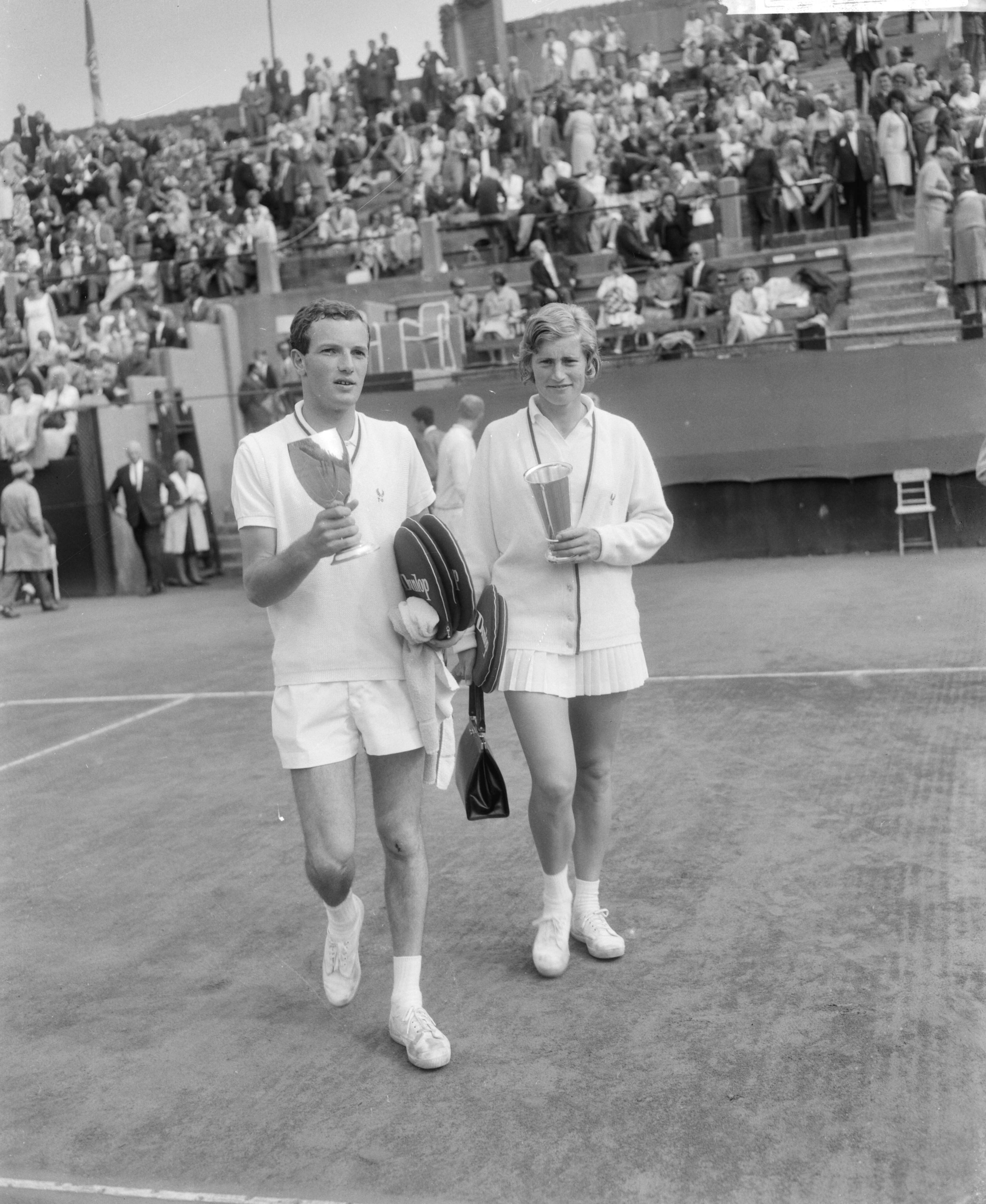 Fotocollectie Anefo — Nederlandse tenniskampioenschappen op de METS-banen te Scheveningen, Tom Okker en Trudy Groenman, winnaars van het enkelspel, met hun bekers — Foto: Bilsen, Joop van / Anefo. Licentie: Set B: Rechtenvrij / Publiek Domein. Bron: Nationaal Archief. http://hdl.handle.net/10648/aabb3bec-d0b4-102d-bcf8-003048976d84