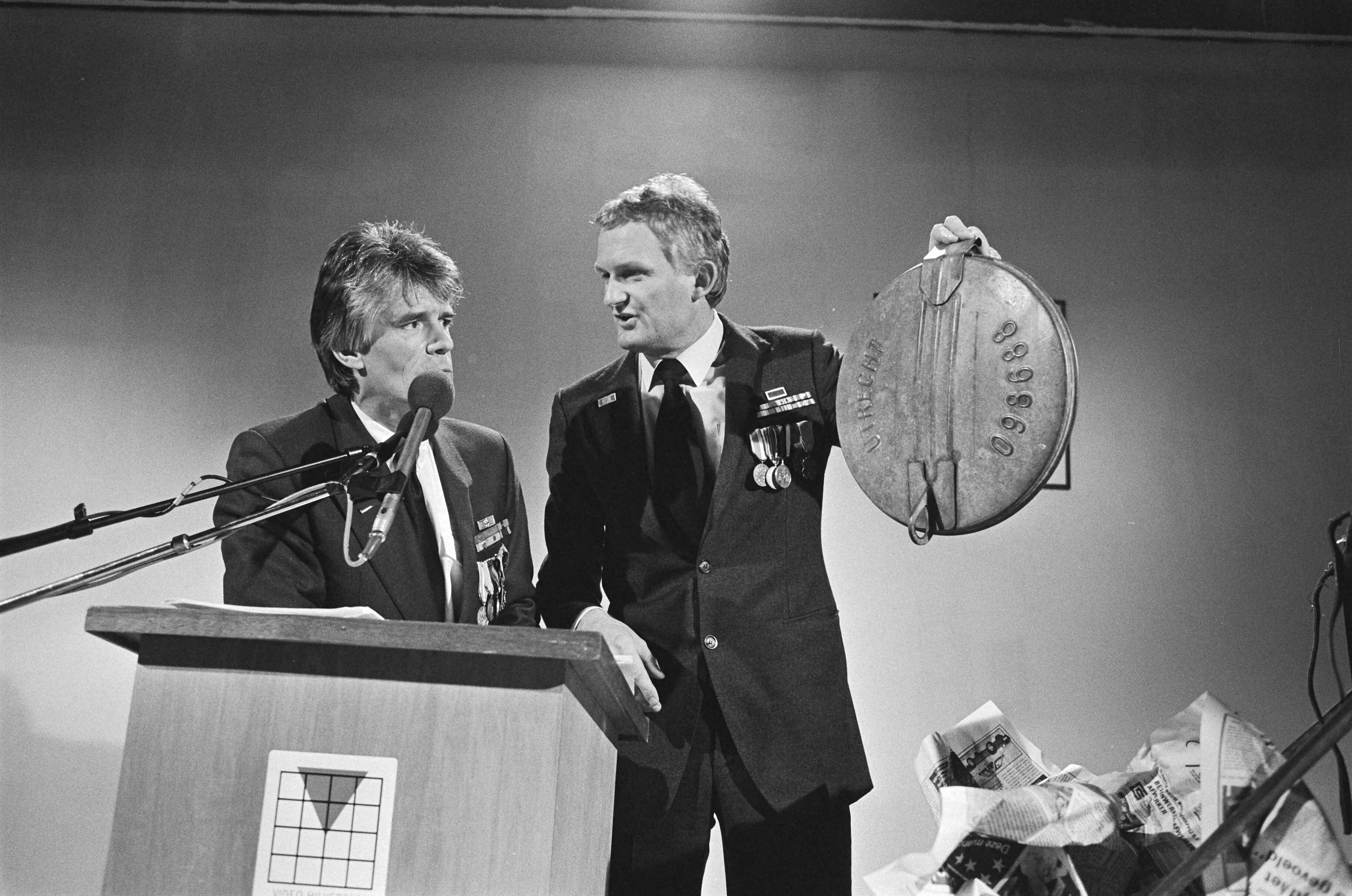 Fotocollectie Anefo — Uitreiking Nipkowschrijf in Hilversum; Van Kooten (links) en De Bie achter de microfoon (close) — Foto: Bogaerts, Rob / Anefo. Licentie: Set B: Rechtenvrij / Publiek Domein. Bron: Nationaal Archief. http://hdl.handle.net/10648/ad4aa44c-d0b4-102d-bcf8-003048976d84