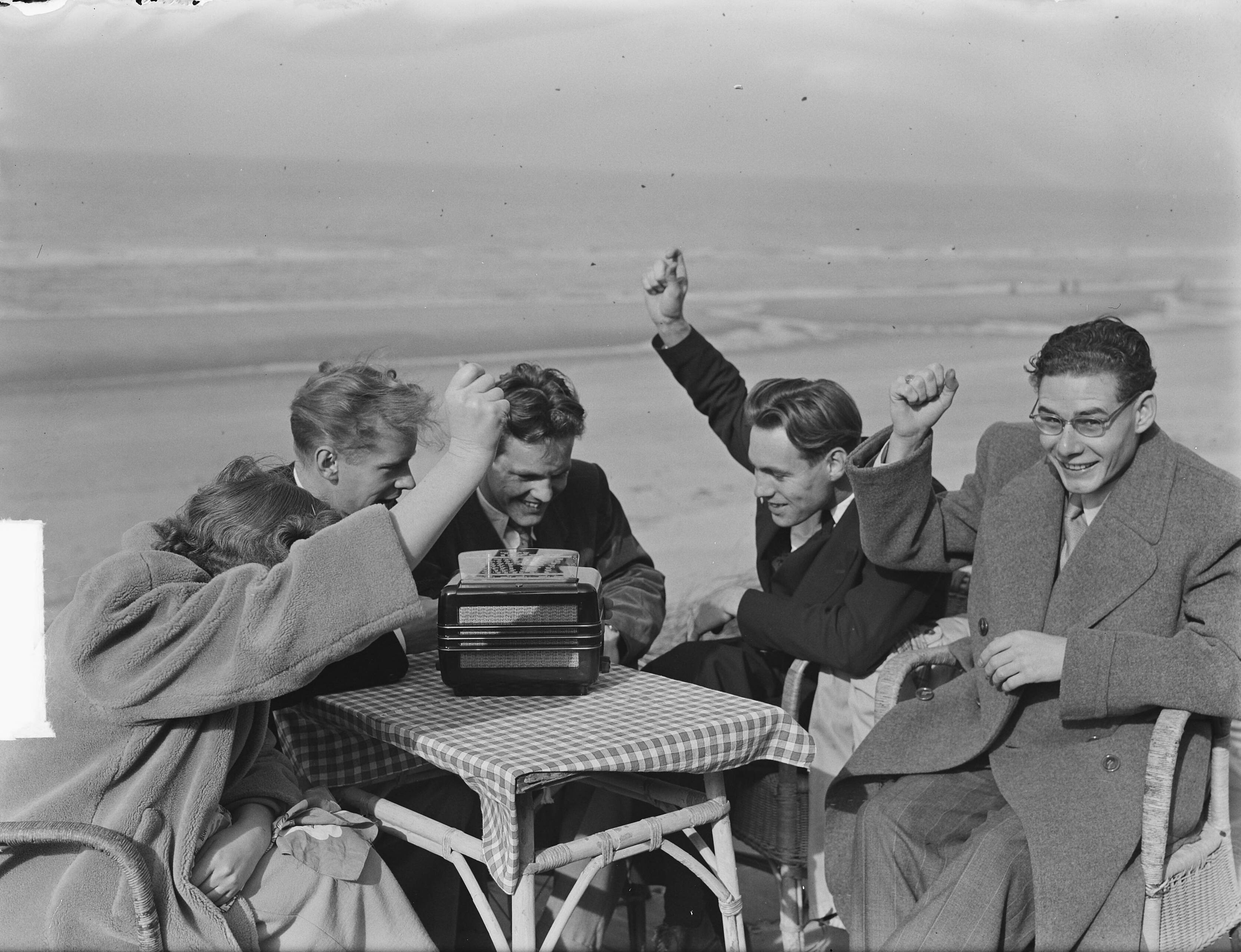 Fotocollectie Anefo — In Zandvoort luisteren mensen naar het radioverslag van de voetbalwedstrijd Zwitserland tegen Nederland [juichen bij doelpunt] — Foto: Pot, Harry / Anefo. Licentie: Set B: Rechtenvrij / Publiek Domein. Bron: Nationaal Archief. http://hdl.handle.net/10648/a8e0c666-d0b4-102d-bcf8-003048976d84