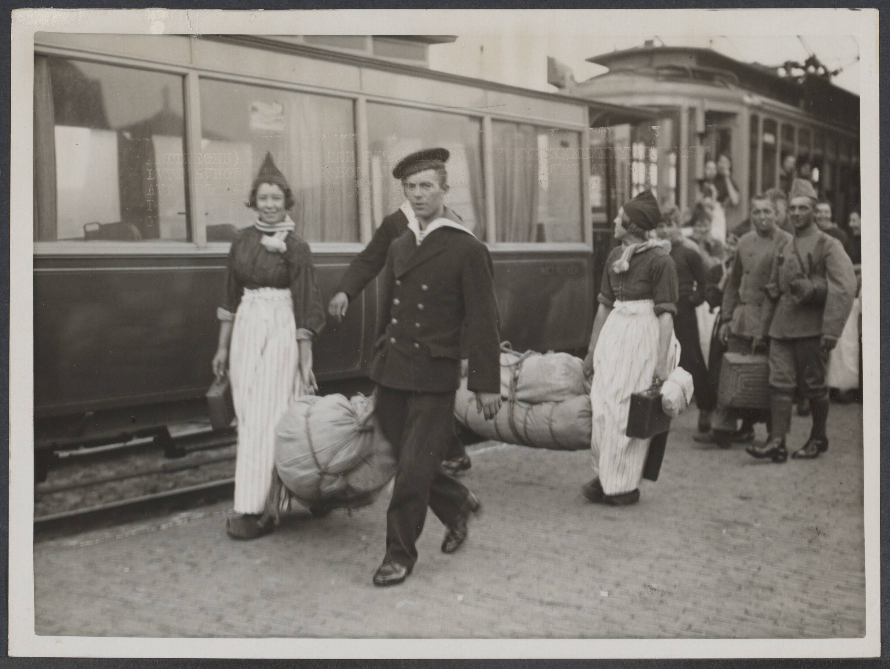 Mobilisatie; voorgeschiedenis W.O.II enz. - Nederland — Volendam. 29 augustus 1939. De eerste dag van het mobilisatie-bevel. Duizenden militairen moesten zich hedenmorgen per vroegste gelegenheid naar hun garnizoen begeven. Volendamse meisjes brengen hun gemobilseerde verloofden naar het trammetje, dat hen naar een der spoorwegstations moet vervoeren — Foto: N.V. Polygoon. Licentie: Set B: Rechtenvrij / Publiek Domein. Bron: Nationaal Archief. http://hdl.handle.net/10648/e9ac0872-3b5f-c50e-909f-f50b7980e555