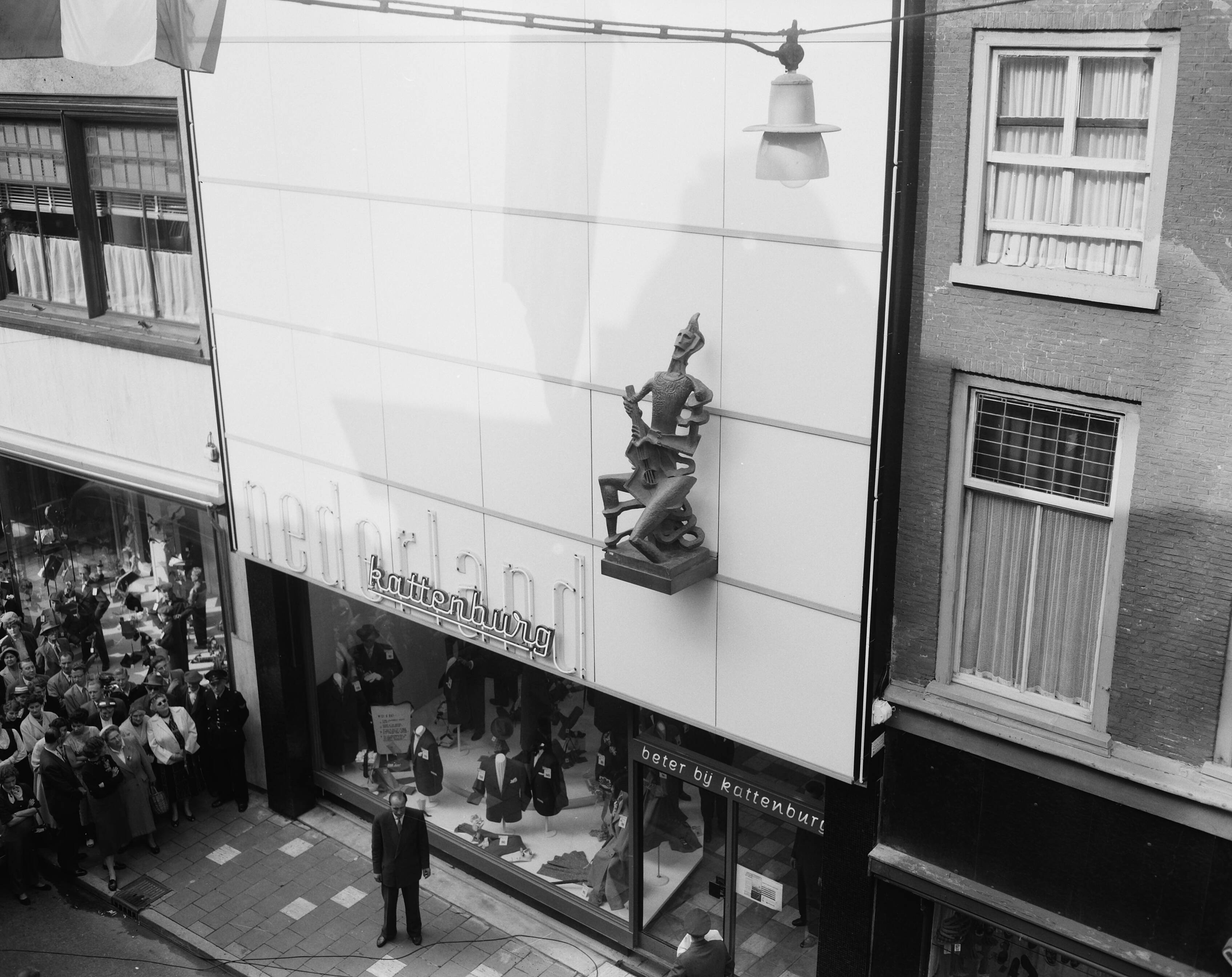 Fotocollectie Anefo — Onthulling beeld "De Harlekijn" van Ossip Zadkine op gevel van modehuis N.V. Kattenburg te Haarlem — Foto: Noske, J.D. / Anefo. Licentie: Set B: Rechtenvrij / Publiek Domein. Bron: Nationaal Archief. http://hdl.handle.net/10648/a94f3d12-d0b4-102d-bcf8-003048976d84