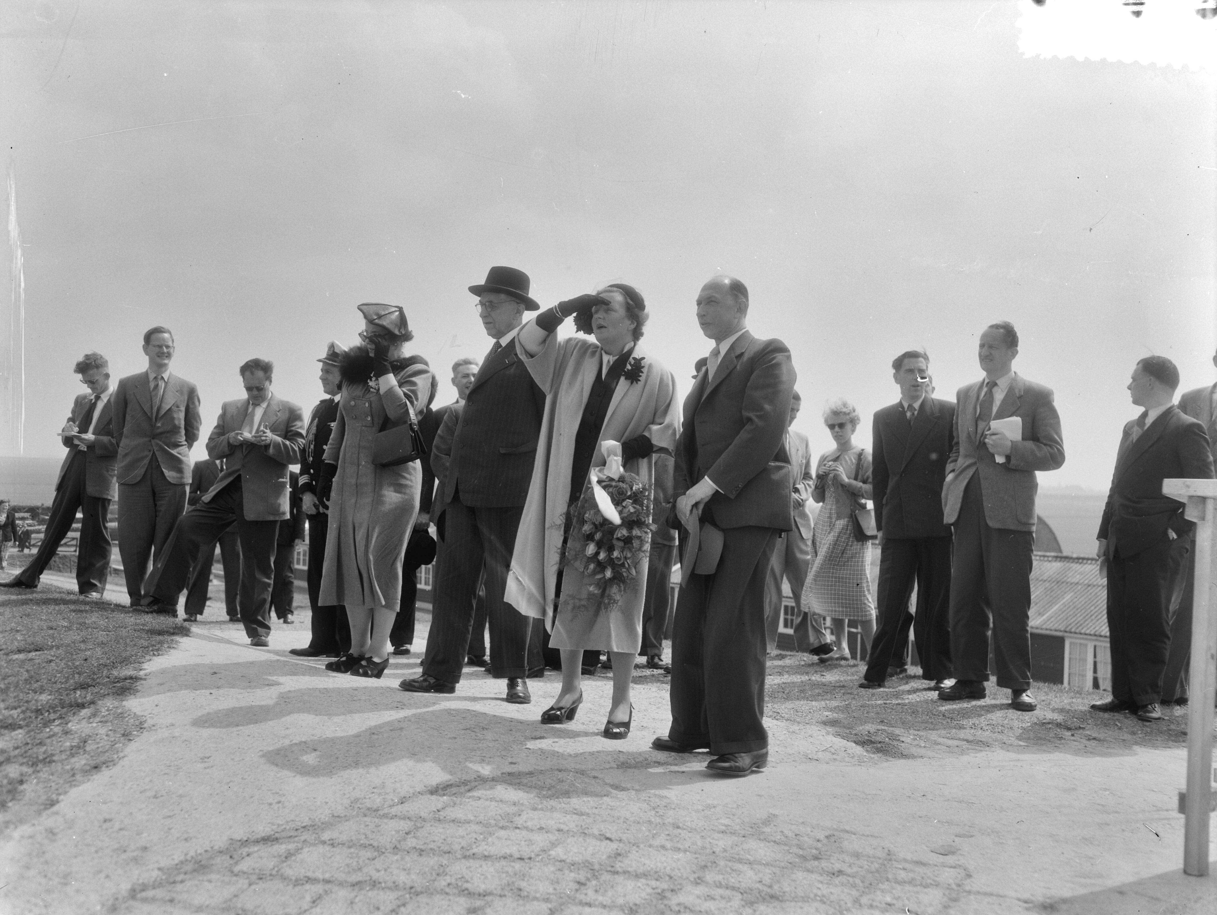 Werkbezoek van koningin Juliana aan de provincie Groningen (1954) — Werkbezoek van koningin Juliana aan de provincie Groningen. Op de zeedijk bij de Julianapolder, waar de koningin een uitzicht had over de Waddenzee en de landaanwinningswerken bekeek. Rechts van haar ir. W. Kooper, hoofdingenieur van Rijkswaterstaat en hoofd van de Dienst Landaanwinningswerken. Links Commissaris der Koningin dr, E.H. Ebels, In het midden de particuliere secretaresse van de koningin, mevr. Smitt-Avis en de adjudant van de koningin, kapitein-luitenant-ter-zee J.G. Stegeman — Foto: Duinen, G.W. van / Anefo. Licentie: Set B: Rechtenvrij / Publiek Domein. Bron: Nationaal Archief. http://hdl.handle.net/10648/a9229140-d0b4-102d-bcf8-003048976d84