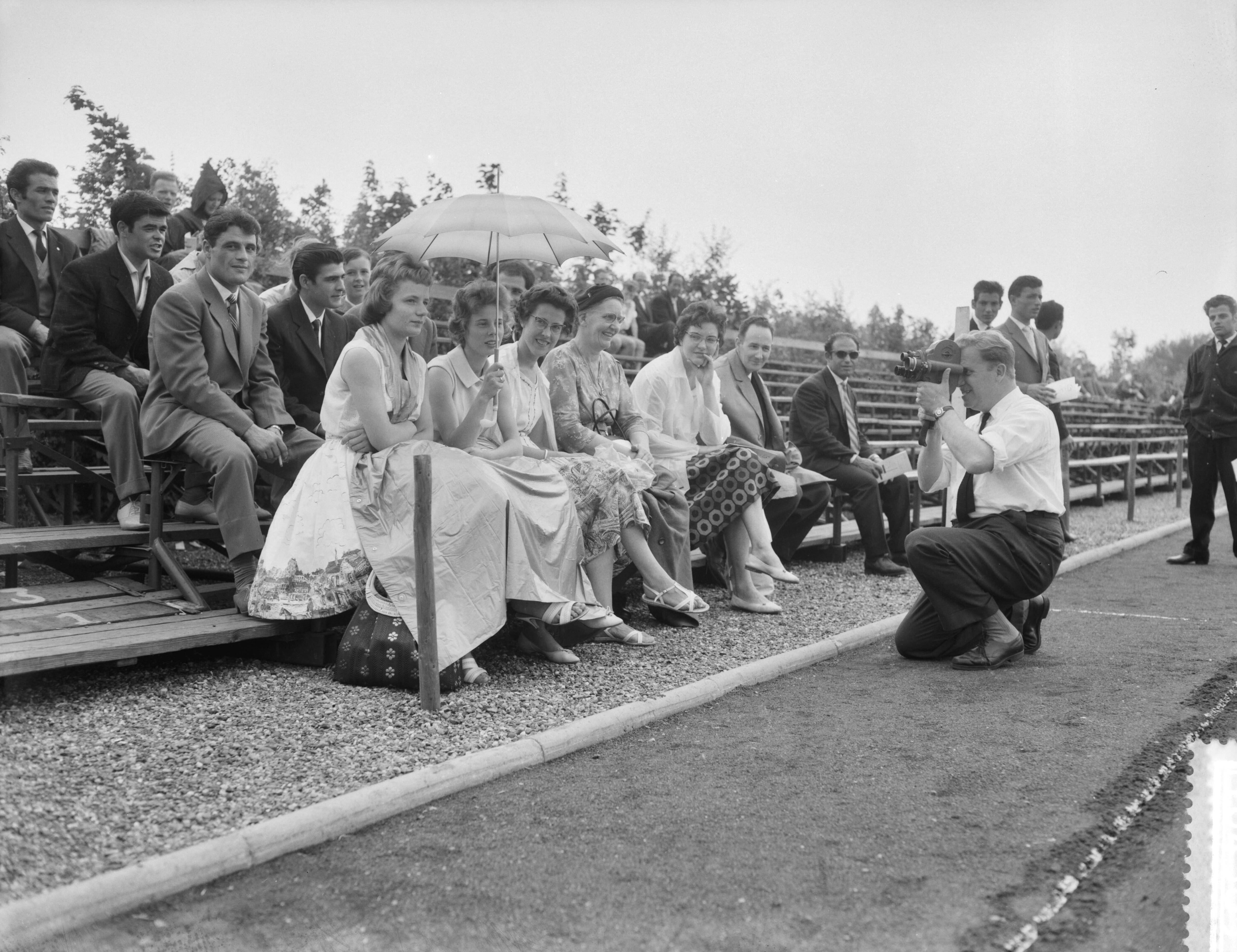 Fotocollectie Anefo — Atletiekwedstrijden dames Nederland tegen Italië te Maastricht, toeschouwsters onder paraplu tijdens regenbuitje — Foto: Rossem, Wim van / Anefo. Licentie: Set B: Rechtenvrij / Publiek Domein. Bron: Nationaal Archief. http://hdl.handle.net/10648/a996e626-d0b4-102d-bcf8-003048976d84