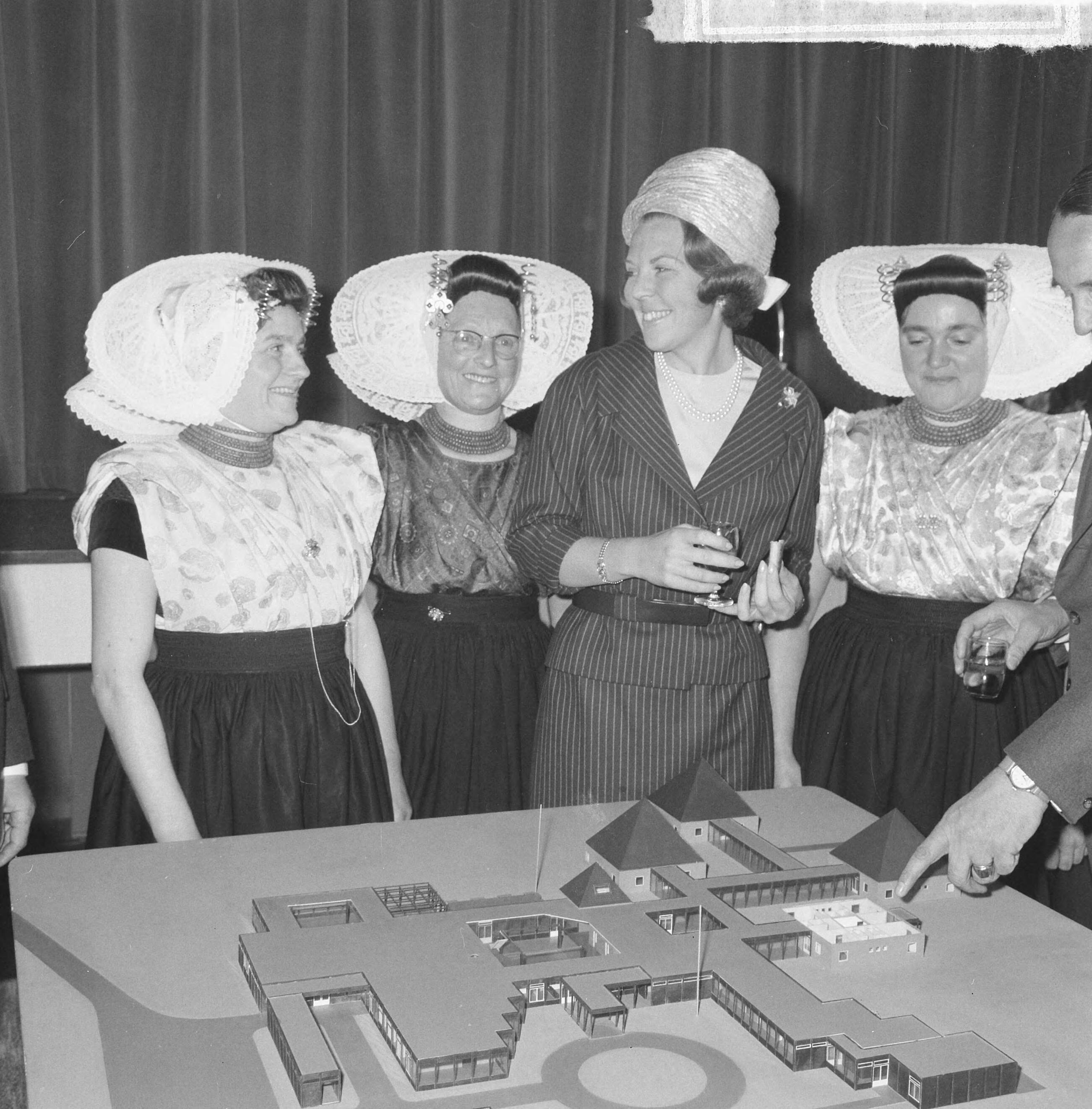 Fotocollectie Anefo — Prinses Beatrix was aanwezig bij de eerste steenlegging voor het jongerenontmoetingscentrum "Het Zilveren Schor" nabij Arnemuiden, prinses Beatrix tussen dames in klederdracht. Voor haar de maquette van het gebouw, een ontwerp van architect Onno Greiner — Foto: Nijs, Jac. de / Anefo. Licentie: Set B: Rechtenvrij / Publiek Domein. Bron: Nationaal Archief. http://hdl.handle.net/10648/aaa1bdca-d0b4-102d-bcf8-003048976d84