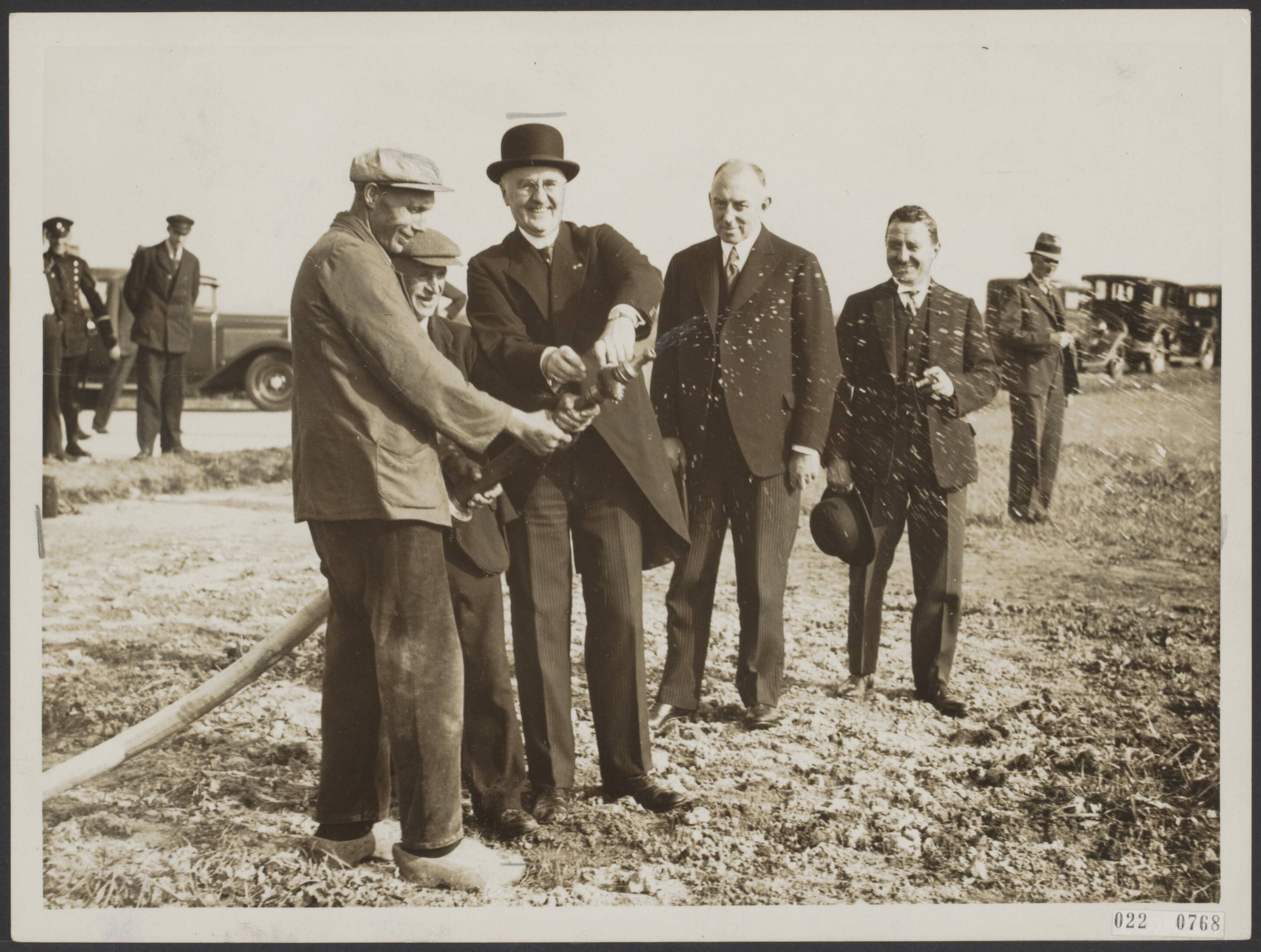 Fotocollectie Elsevier Binnenland — Heden had de officiële opening plaats van het pompstation van de Groninger Provinciale Waterleiding, welk station gelegen is in de Onnerpolder aan een zijweg van de weg Onnen-Noord-Laren. Commissaris der Koningin Dr. J.P. Fockema Andrea opent de brandkraan die het water voor de aanwezigen zichtbaar maakt. Achter hem burgemeester van Groningen H.P.J. Bloemers en de heer W.F.J.M. Krul van het Rijksbureau van de Drinkwatervoorziening te Den Haag — Foto: N.V. Polygoon. Licentie: Set B: Rechtenvrij / Publiek Domein. Bron: Nationaal Archief. http://hdl.handle.net/10648/add31872-d0b4-102d-bcf8-003048976d84