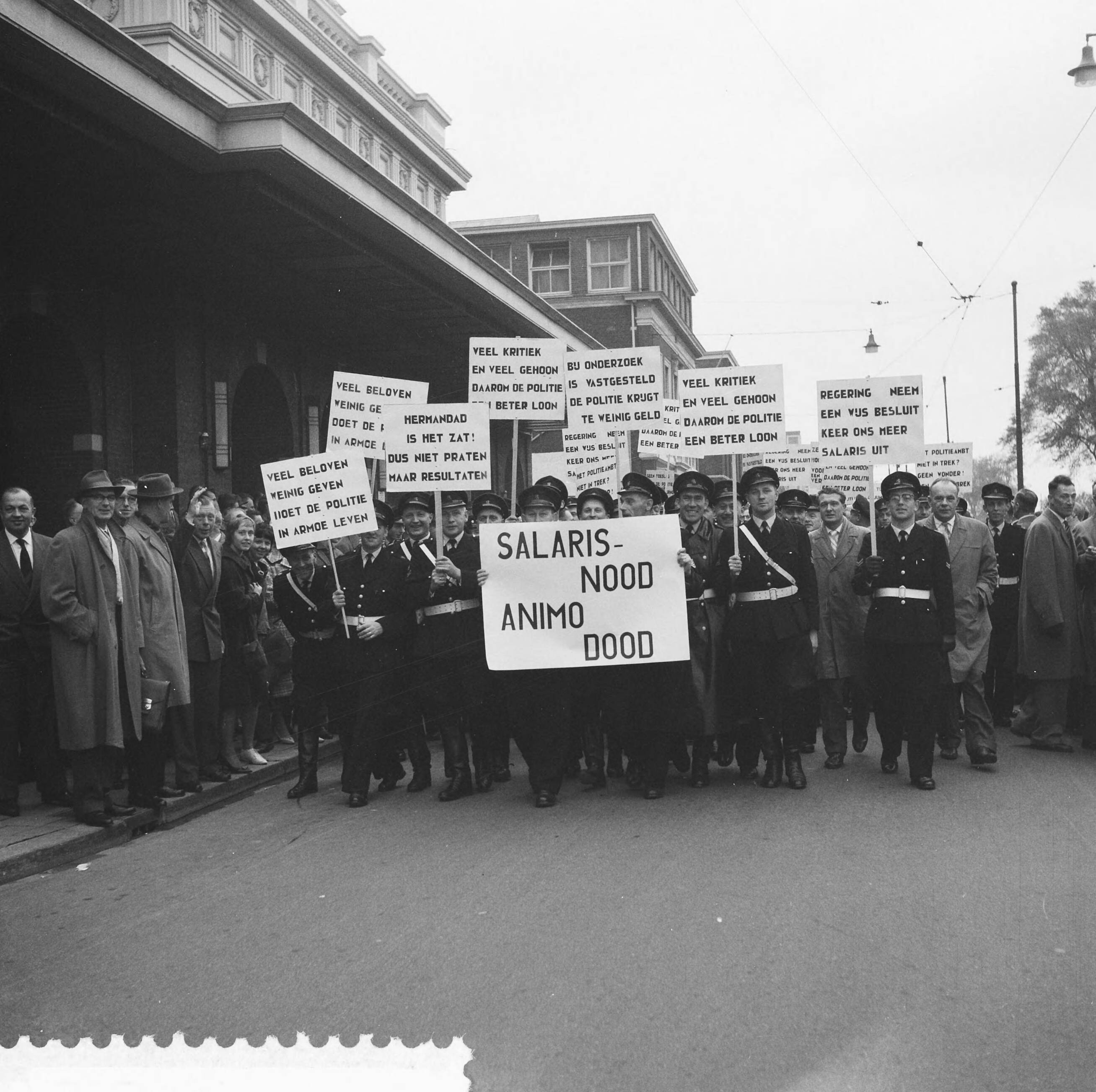 Fotocollectie Anefo — Protestvergadering door politie-ambtenaren tegen loonpolitiek van de regering in het gebouw voor Kunsten en Wetenschappen te Den Haag — Foto: Pot, Harry / Anefo. Licentie: Set B: Rechtenvrij / Publiek Domein. Bron: Nationaal Archief. http://hdl.handle.net/10648/a9bc3e80-d0b4-102d-bcf8-003048976d84
