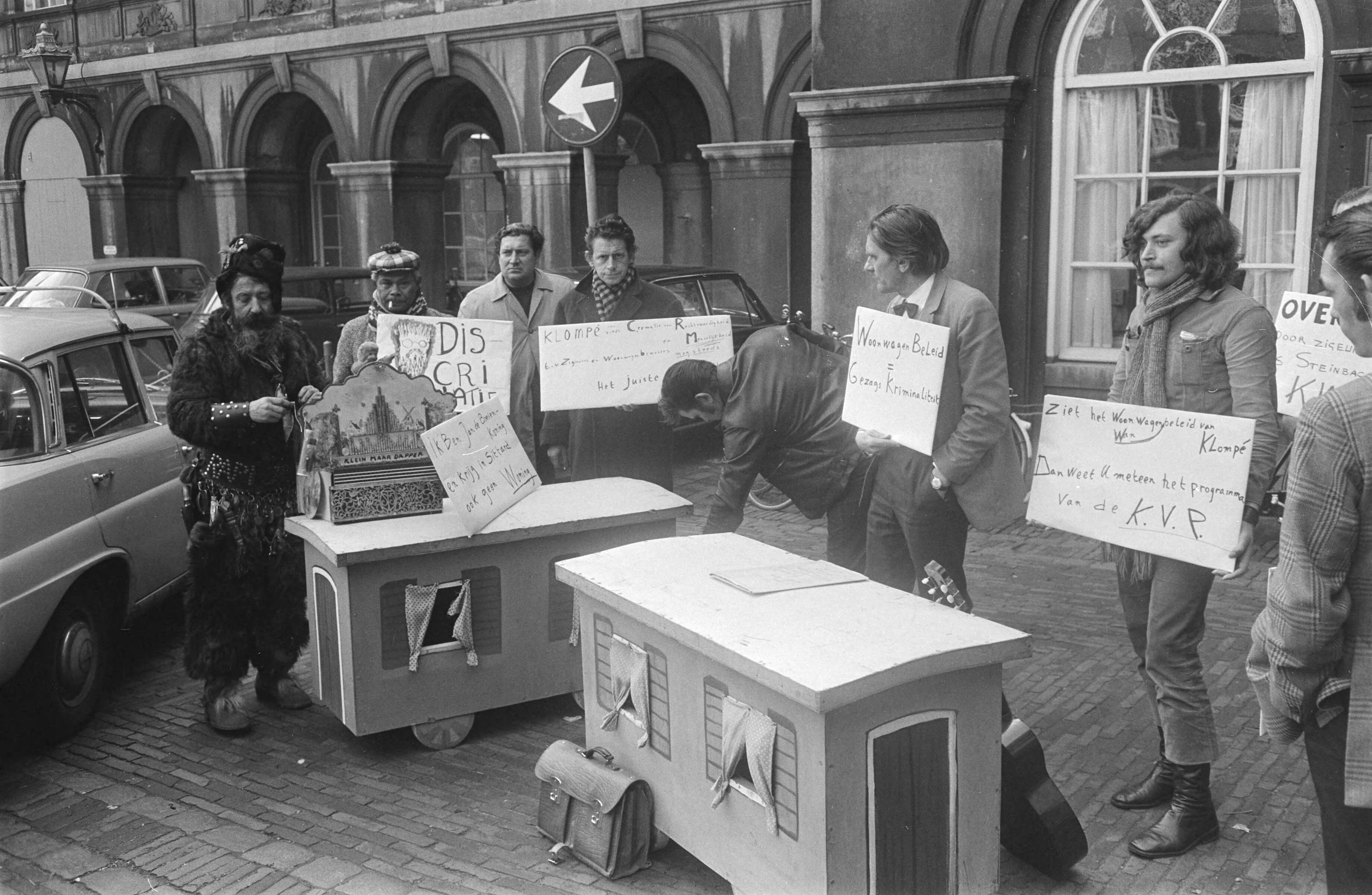 Protestdemonstratie op het Binnenhof in Den Haag tegen het woonwagenbeleid — Demonstranten protesteren met kartonnen mini-woonwagens en borden — Foto: Fotograaf Onbekend / Anefo. Licentie: Set B: Rechtenvrij / Publiek Domein. Bron: Nationaal Archief. http://hdl.handle.net/10648/abb75a62-d0b4-102d-bcf8-003048976d84