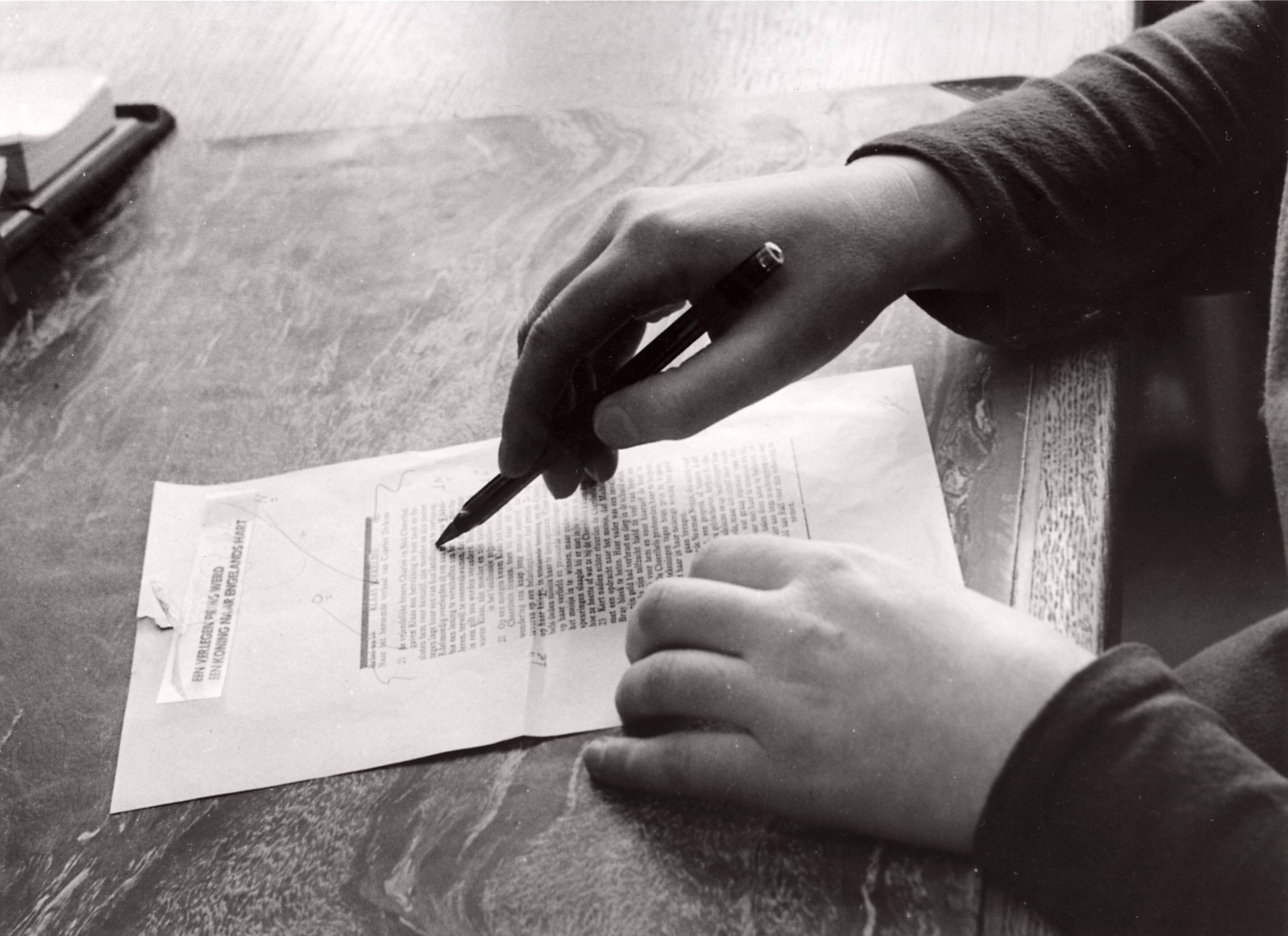 Sportactiviteiten personeel Drukkerij N.V. De Spaarnestad / diversen — [Serie: Drukkerij N.V. Spaarnestad] [de hand en pen van een corrector bij een artikel/verhaal "Klaas Nikkelbie" (naar het beroemde verhaal van Charles Dickens [Nicolas Nickleby]. Boven een kop "een verlegen prins werd een koning naar Engelands hart" — Foto: Fotograaf Onbekend / Fotobureau onbekend / Spaarnestad Photo (05887). Licentie: Set B: Rechtenvrij / Publiek Domein. Bron: Nationaal Archief. http://hdl.handle.net/10648/35429da6-3f5c-a382-e063-6df0900a6686
