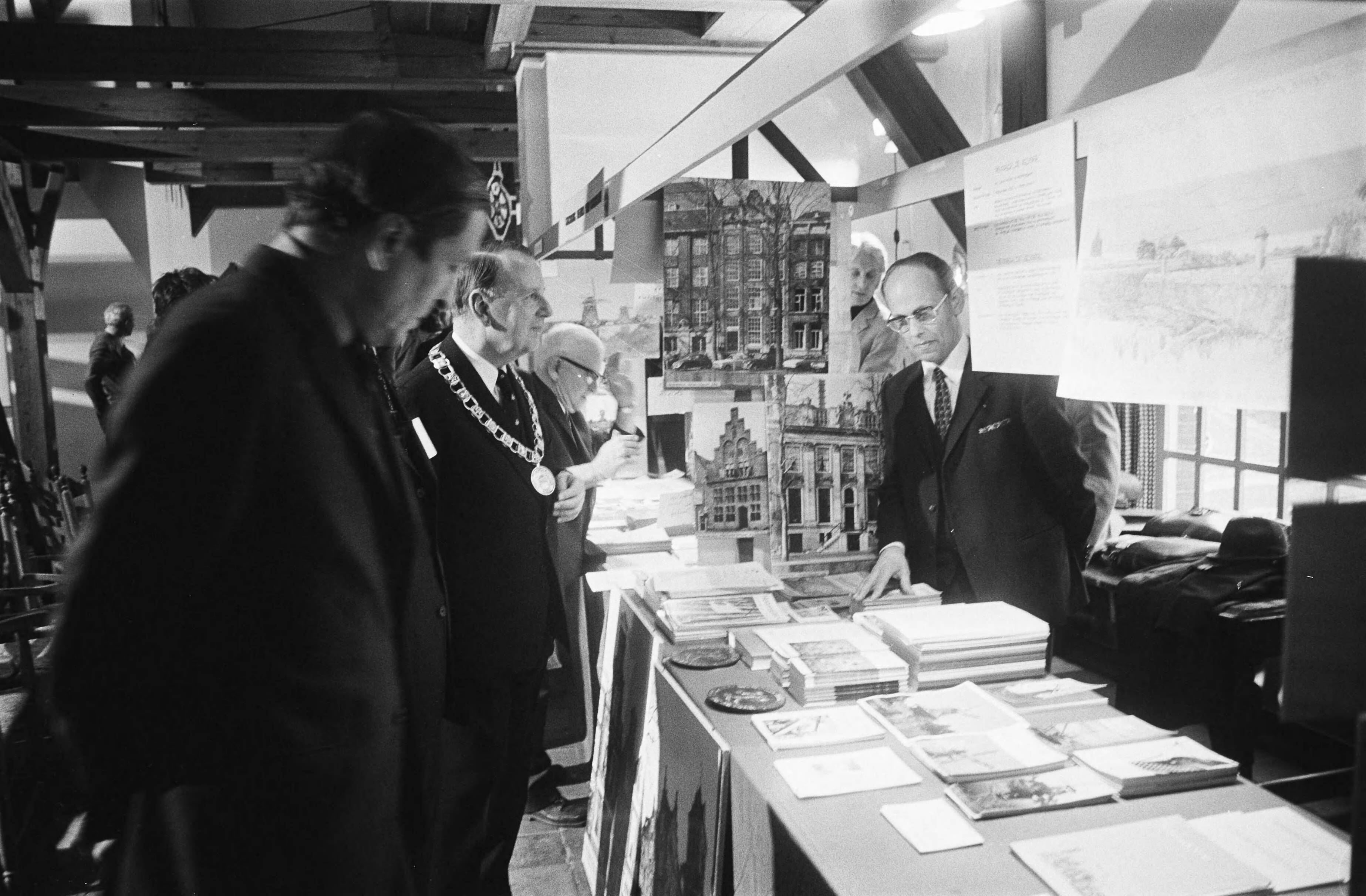 Fotocollectie Anefo — In functie van erevoorzitter Nationaal Comité Monumentenjaar 1975 overhandigde Prins Claus aan de burgemeesters van tien gemeenten de nieuw ontworpen Monumentenvlag in Slot van Zeist . Na de officiële opening in de Slotzaal van Slot Zeist van het Monumentenjaar 1975 maakte prins Claus in gezelschap van burgemeester Stolk een rondwandeling over de informatiemarkt op de Congreszolder omtrent het Monumentenjaar 1975 — Foto: Peters, Hans / Anefo. Licentie: Set B: Rechtenvrij / Publiek Domein. Bron: Nationaal Archief. http://hdl.handle.net/10648/ac5d6650-d0b4-102d-bcf8-003048976d84