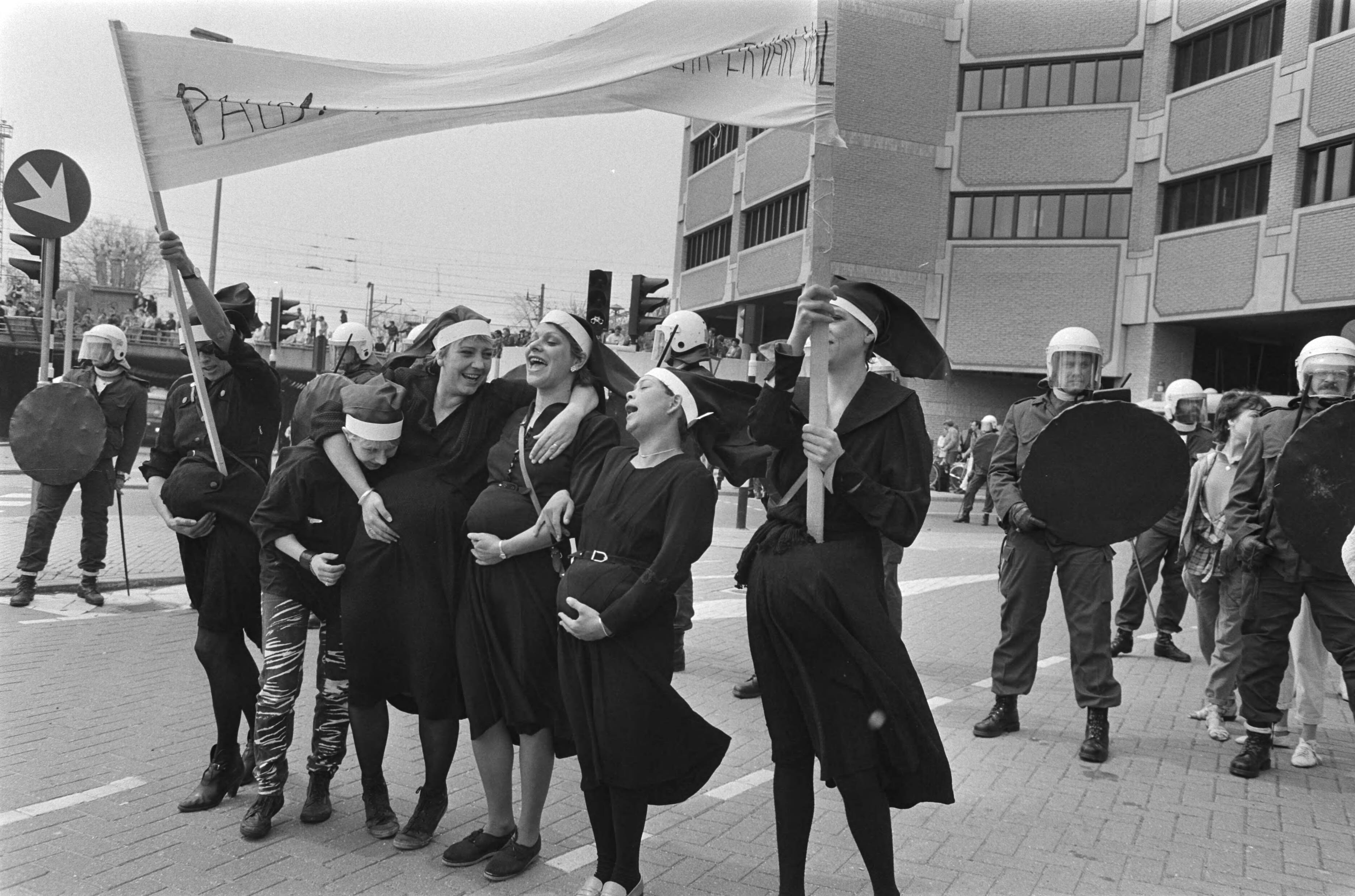 Fotocollectie Anefo — Demonstratie tegen Pausbezoek in Utrecht; als nonnen verklede demonstranten voor het cordon ME — Foto: Vollebregt, Sjakkelien / Anefo. Licentie: Set B: Rechtenvrij / Publiek Domein. Bron: Nationaal Archief. http://hdl.handle.net/10648/ad469b5e-d0b4-102d-bcf8-003048976d84