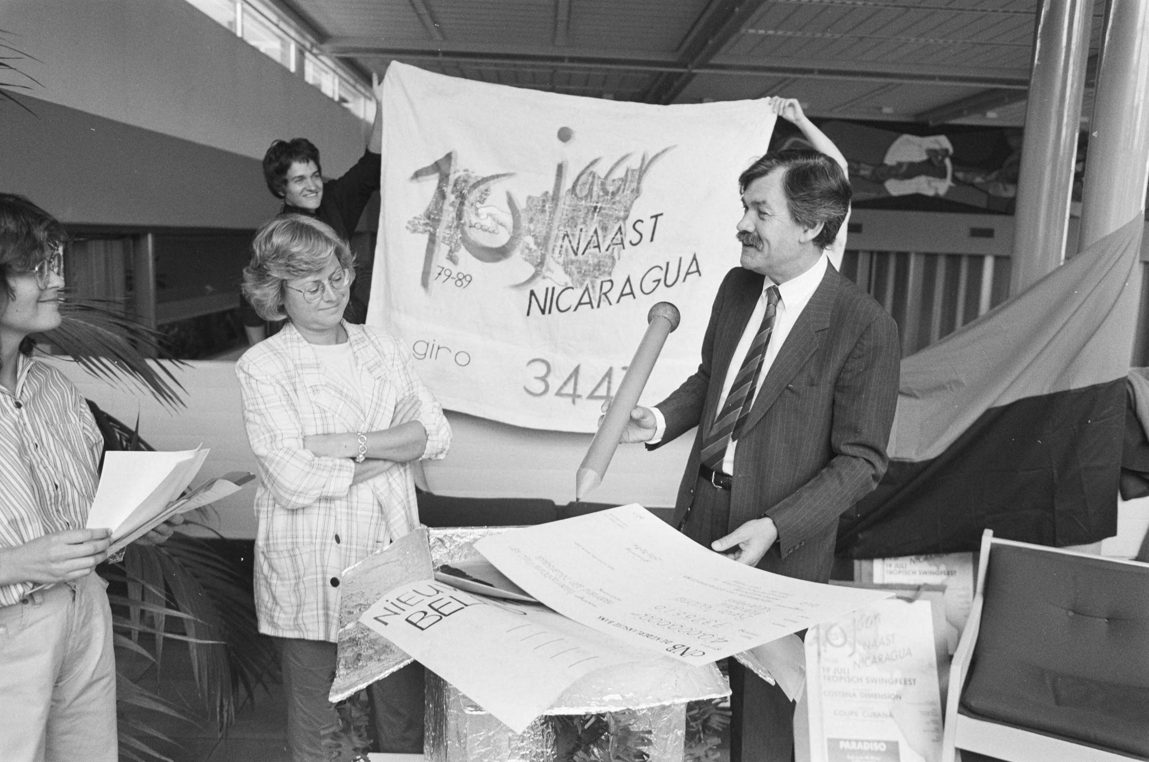 Fotocollectie Anefo — In verband met de tiende verjaardag van de revolutie in Nicaragua kregen Eveline Herfkens (lid Tweede Kamer der Staten-Generaal) en Jan-Willem Bertens (ambassadeur internationale culturele samenwerking, ministerie van Buitenlandse Zaken) in Hilversum een cheque van 40 miljoen — Foto: Croes, Rob C. / Anefo. Licentie: Set B: Rechtenvrij / Publiek Domein. Bron: Nationaal Archief. http://hdl.handle.net/10648/ad73ed20-d0b4-102d-bcf8-003048976d84