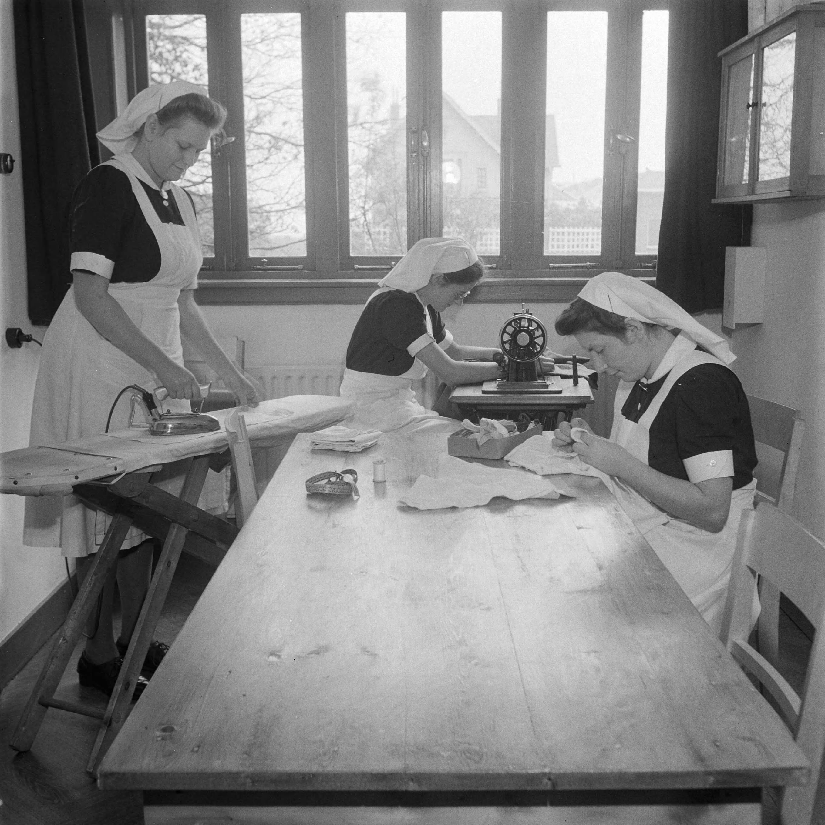 Verpleegstersschool — De eerste Katholieke Opleiding voor Verpleegkundigen in Park Vronesteyn in Voorburg. Drie verpleegkundigenzijn aan het naaien en strijken — Foto: Wisman, Bram / Anefo. Licentie: Set B: Rechtenvrij / Publiek Domein. Bron: Nationaal Archief. http://hdl.handle.net/10648/a8ae438a-d0b4-102d-bcf8-003048976d84