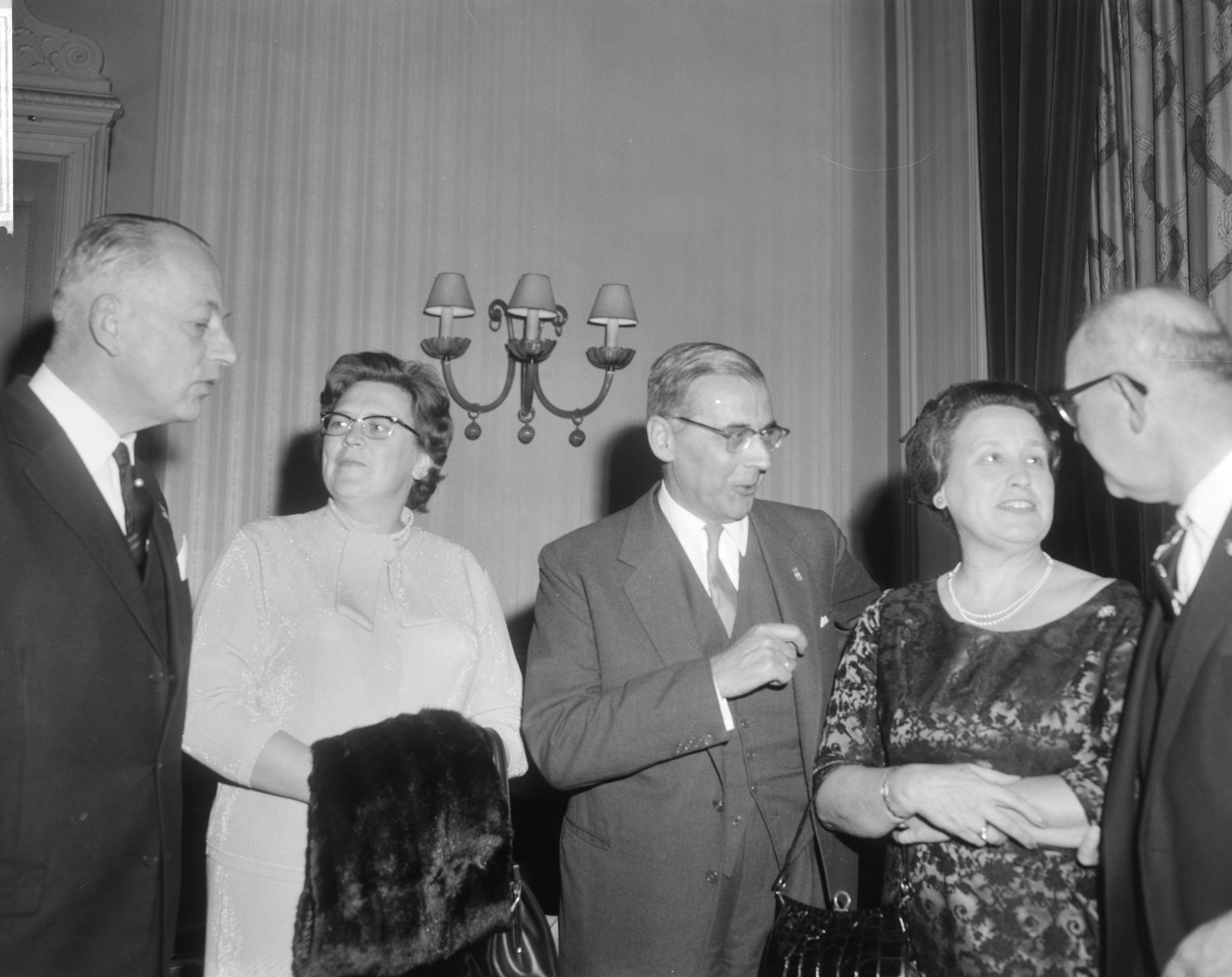 Viering van het tienjarig jubileum van het Nederlands Genootschap van Burgemeesters in het Kurhaus te Scheveningen — Burgemeester van Amsterdam Van Hall (midden) en Burgemeester Kolfschoten van Den Haag (rechts) in gezelschap van twee burgemeestersvrouwen — Foto: Bilsen, Joop van / Anefo. Licentie: Set B: Rechtenvrij / Publiek Domein. Bron: Nationaal Archief. http://hdl.handle.net/10648/aac66bca-d0b4-102d-bcf8-003048976d84