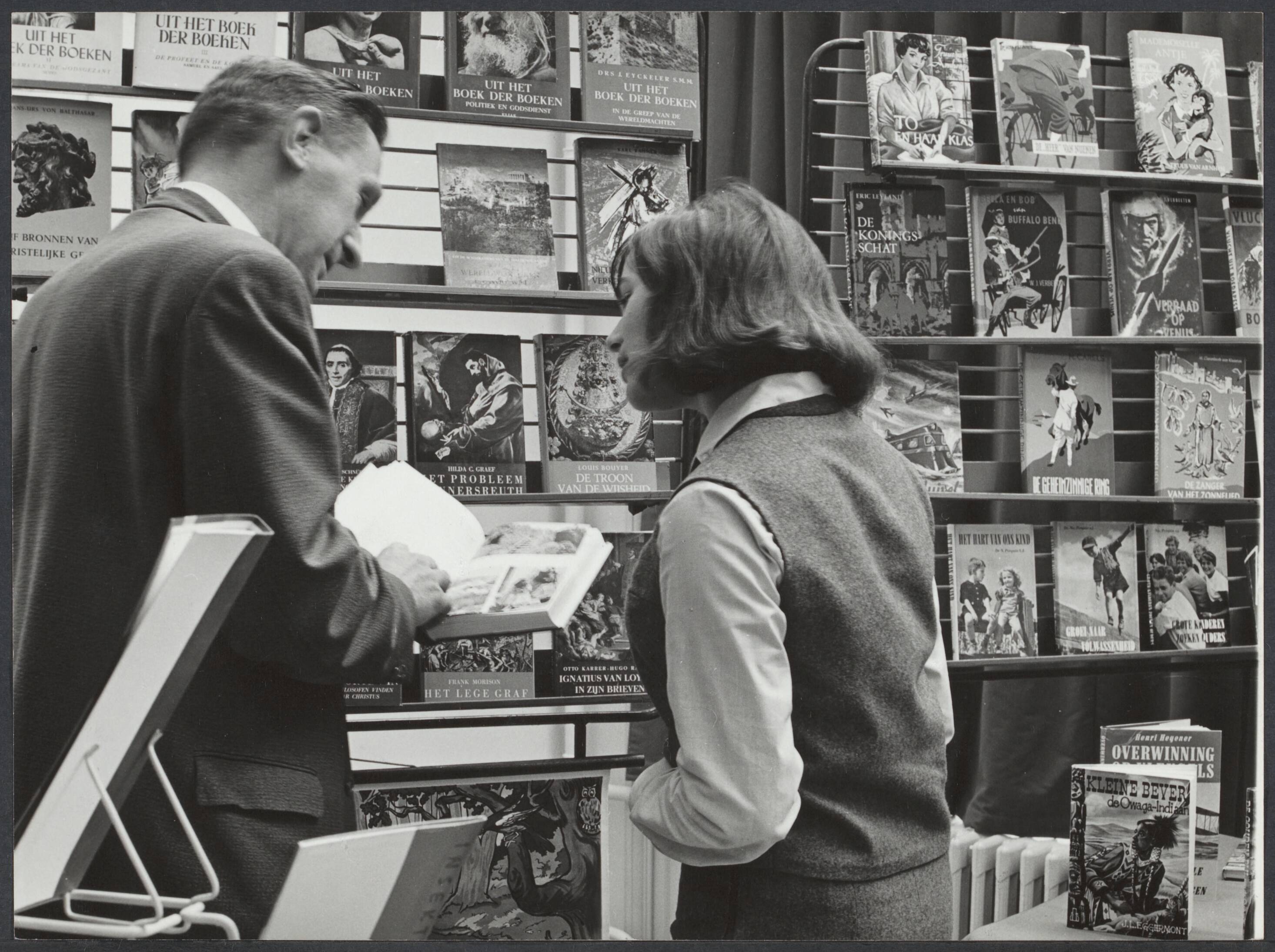 Spaarnestad, winstdeling, personeelsbibliotheek - Nederland — Serie: Personeelsbibliotheek. Dhr. de Vré toont het boek "Portret van Portugal" aan Leni Hei van de markanalyse — Foto: Essenberg, Hans / Spaarnestad / Spaarnestad Photo (05887). Licentie: Set B: Rechtenvrij / Publiek Domein. Bron: Nationaal Archief. http://hdl.handle.net/10648/aaec5053-07f0-11c2-7e13-6376599d283c