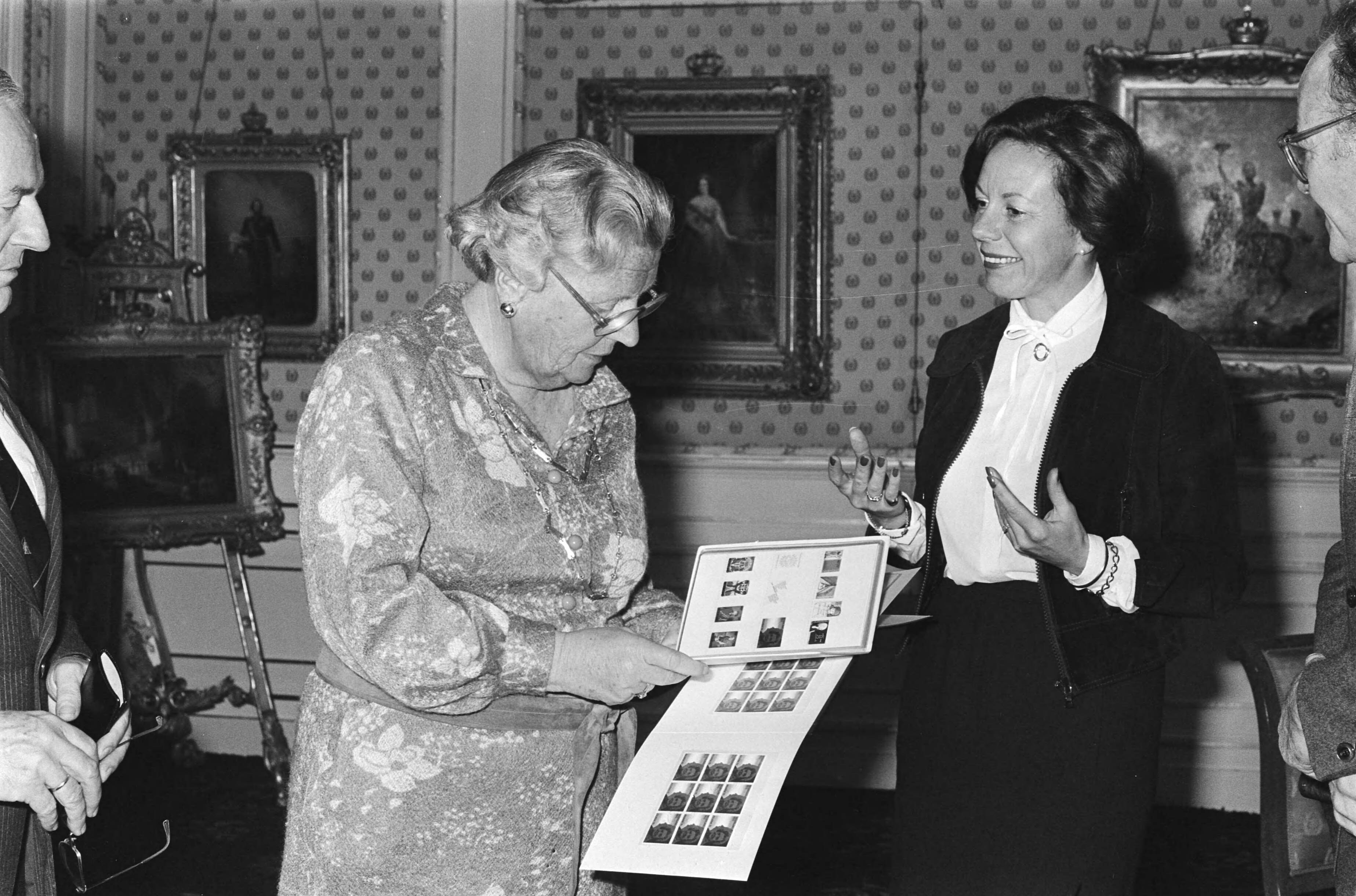Postzegels ter gelegenheid van de 70ste verjaardag van Hare Majesteit door staatssecretaris Smit Kroes uitgereikt aan koningin Juliana op paleis Soestdijk — Smit-Kroes, Neelie|Juliana (koningin Nederland)|Soestdijk|koninginnen |postzegels |staatssecretarissen|Utrecht|Paleis Soestdijk — Foto: Suyk, Koen / Anefo. Licentie: Set B: Rechtenvrij / Publiek Domein. Bron: Nationaal Archief. http://hdl.handle.net/10648/acc6b920-d0b4-102d-bcf8-003048976d84