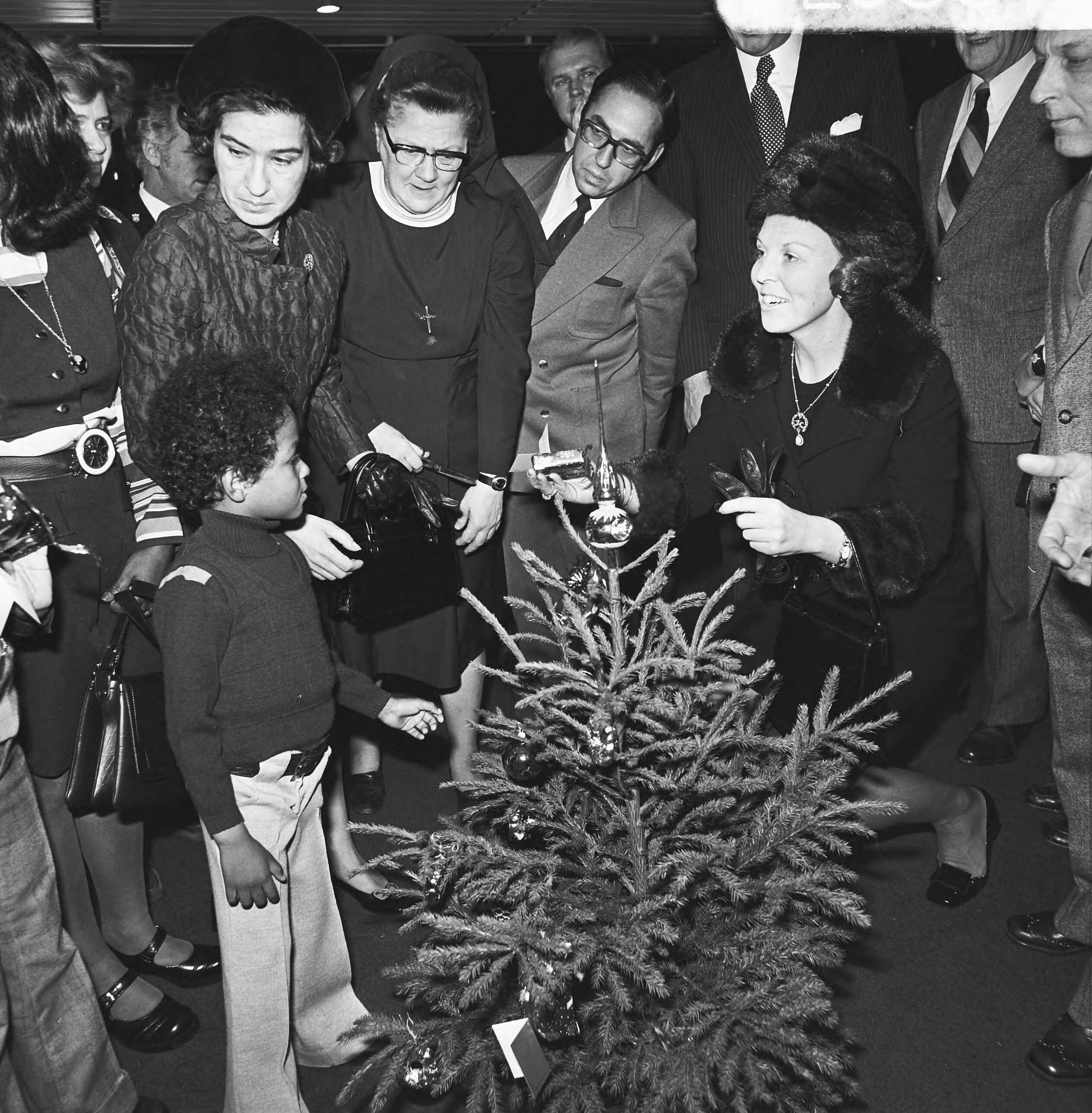 Prinses Beatrix overhandigt de sleutel van de dertigste burgerzinwoning in het stadhuis van Den Haag — De prinses met kinderen en genodigden bij een kerstboom — Foto: Mieremet, Rob / Anefo. Licentie: Set B: Rechtenvrij / Publiek Domein. Bron: Nationaal Archief. http://hdl.handle.net/10648/ac3ed672-d0b4-102d-bcf8-003048976d84