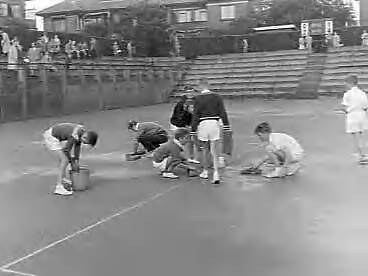 Fotocollectie Anefo — Nationale tenniskampioenschappen op de METS-banen. De baan wordt drooggemaakt door ballenjongens — Foto: Rossem, Wim van / Anefo. Licentie: Set B: Rechtenvrij / Publiek Domein. Bron: Nationaal Archief. http://hdl.handle.net/10648/a967c77e-d0b4-102d-bcf8-003048976d84