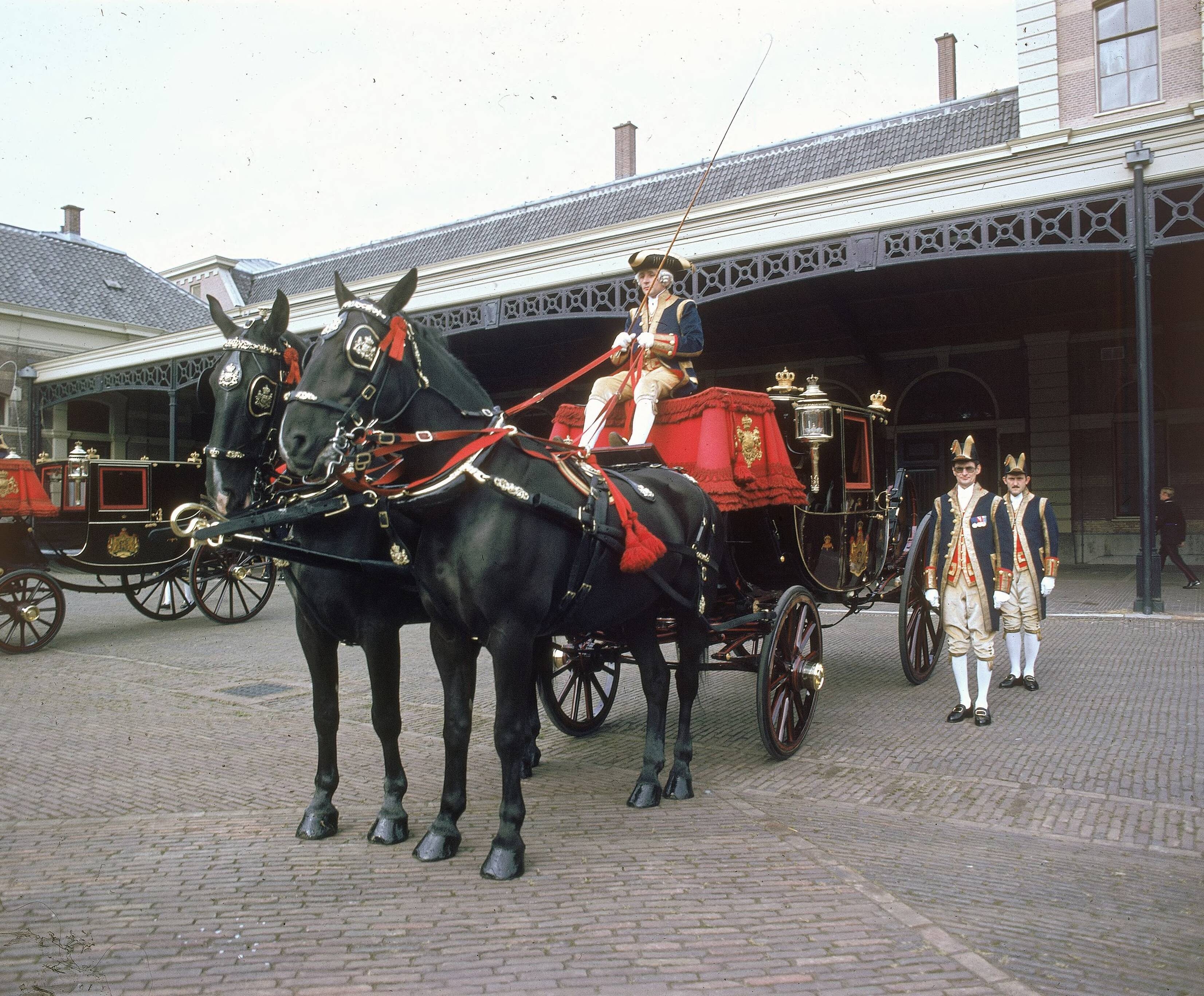 Fotocollectie RVD / Koninklijk Huis — Prinsjesdag - volgrijtuigen, met koetsier, lakeien en paarden op de binnenplaats van de koninklijke stallen aan de Noordwal te Den Haag — Foto: Mastenbroek, Cees / RVD. Licentie: Set B: Rechtenvrij / Publiek Domein. Bron: Nationaal Archief. http://hdl.handle.net/10648/afb274d0-d0b4-102d-bcf8-003048976d84