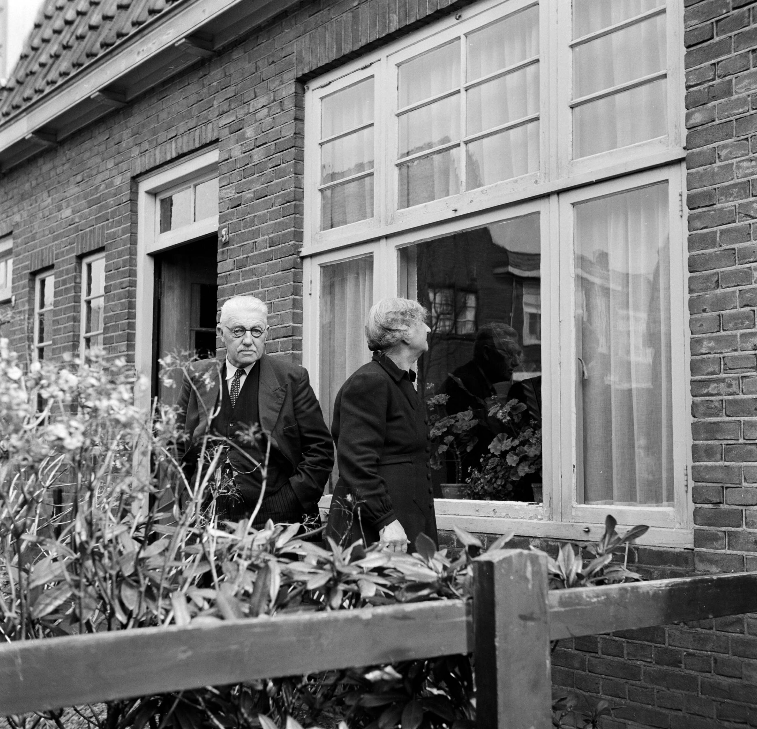 Fotocollectie Van de Poll — Het echtpaar S. de Jong in de tuin voor hun woning in het Friese Huizum (nu deel van Leeuwarden) — Foto: Poll, Willem van de. Licentie: Set B: Rechtenvrij / Publiek Domein. Bron: Nationaal Archief. http://hdl.handle.net/10648/aeccc5c0-d0b4-102d-bcf8-003048976d84